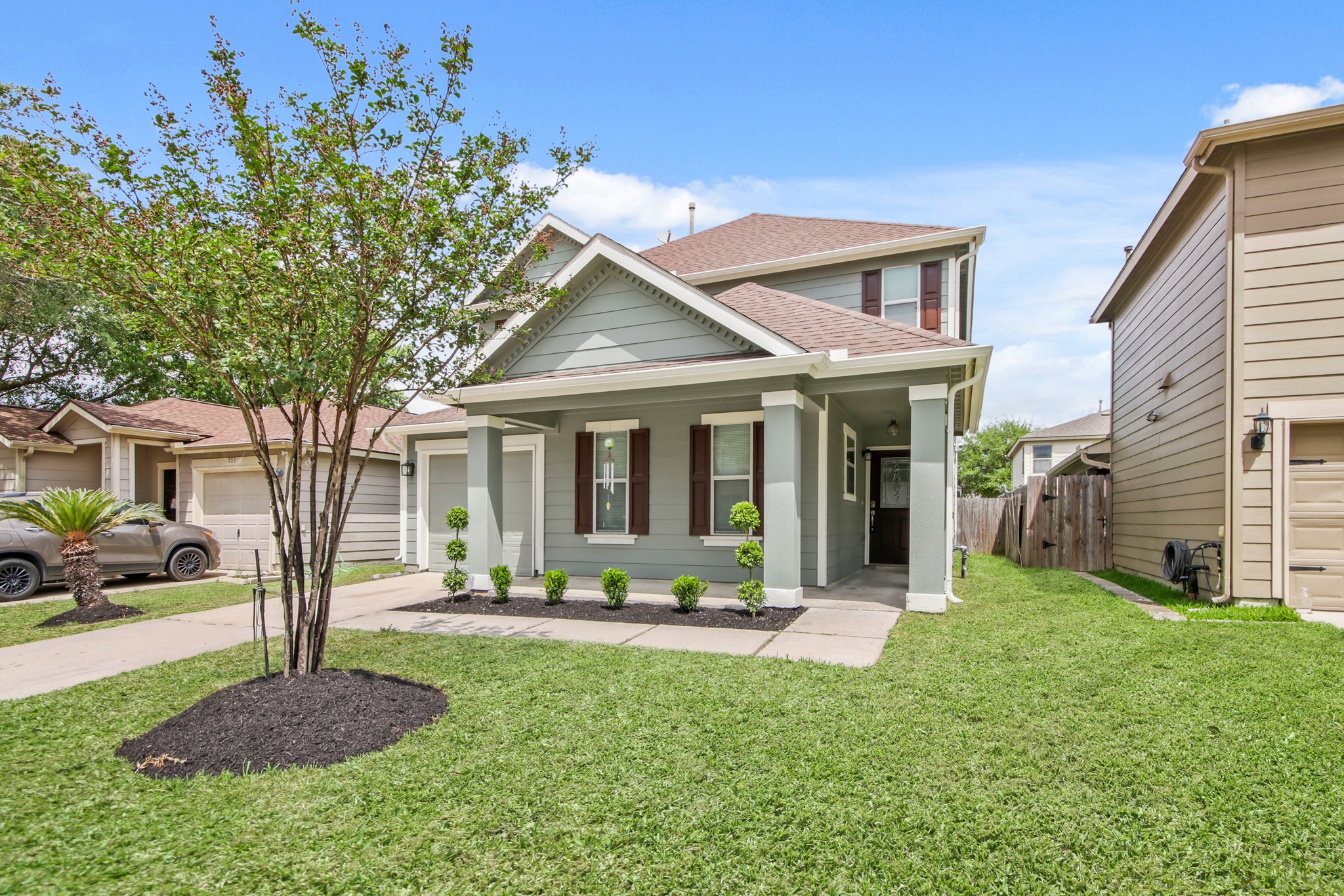A neatly landscaped front yard is highlighted by a central tree and trimmed shrubs. A neatly landscaped front yard is highlighted by a central tree and trimmed shrubs.