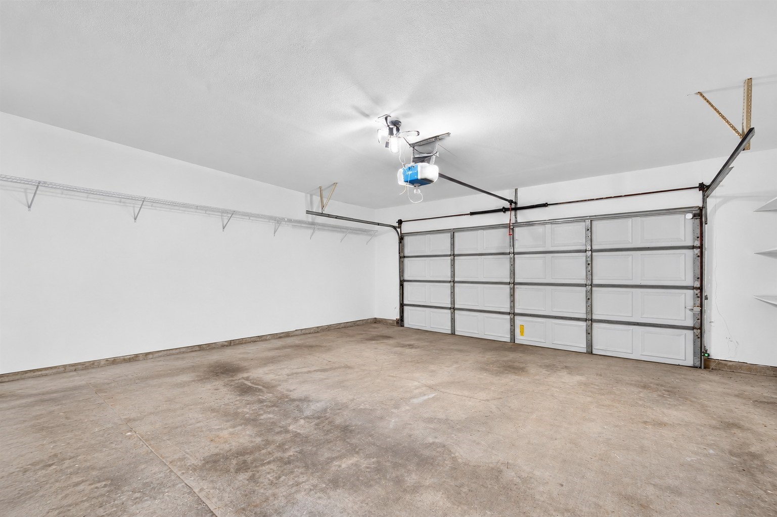 Attached two-car garage with an automatic door opener and storage shelving.