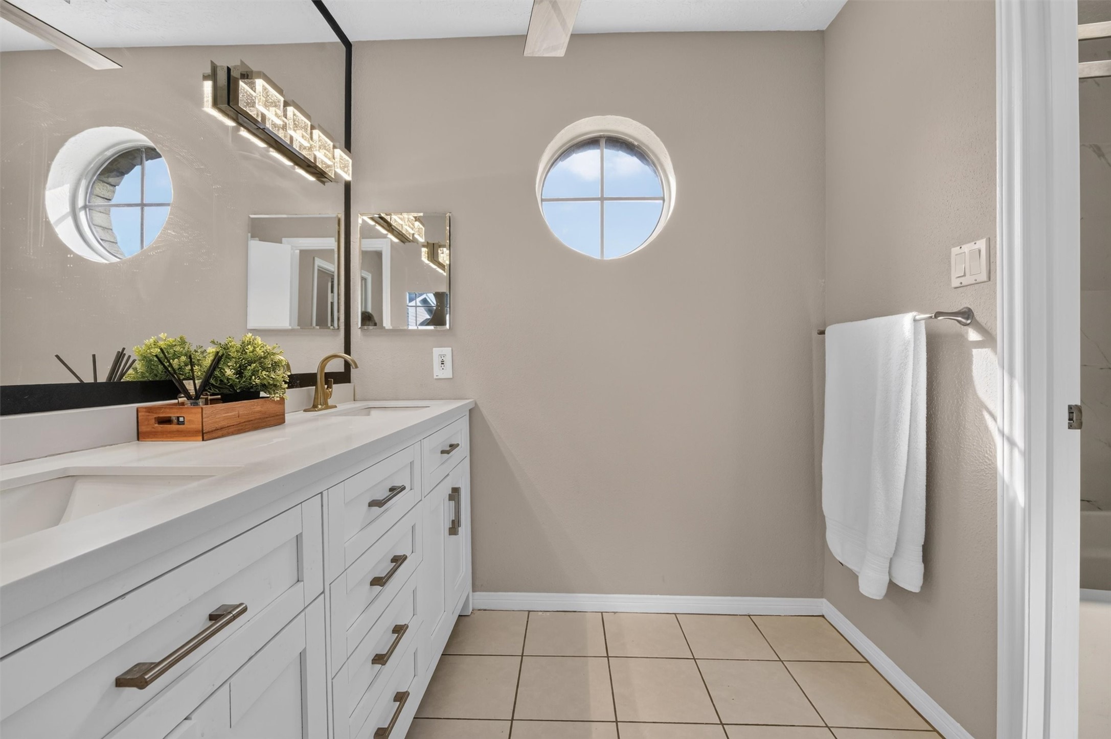 Primary bathroom with a double-sink vanity, generous cabinet storage, and distinctive round windows.