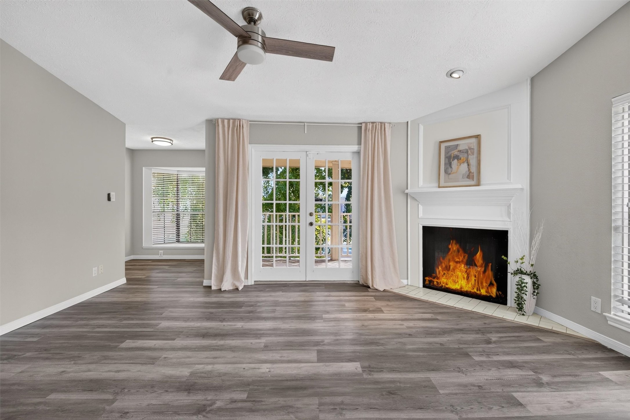 Unstaged primary suite showcasing its spacious layout, fireplace, and French doors to the covered balcony.