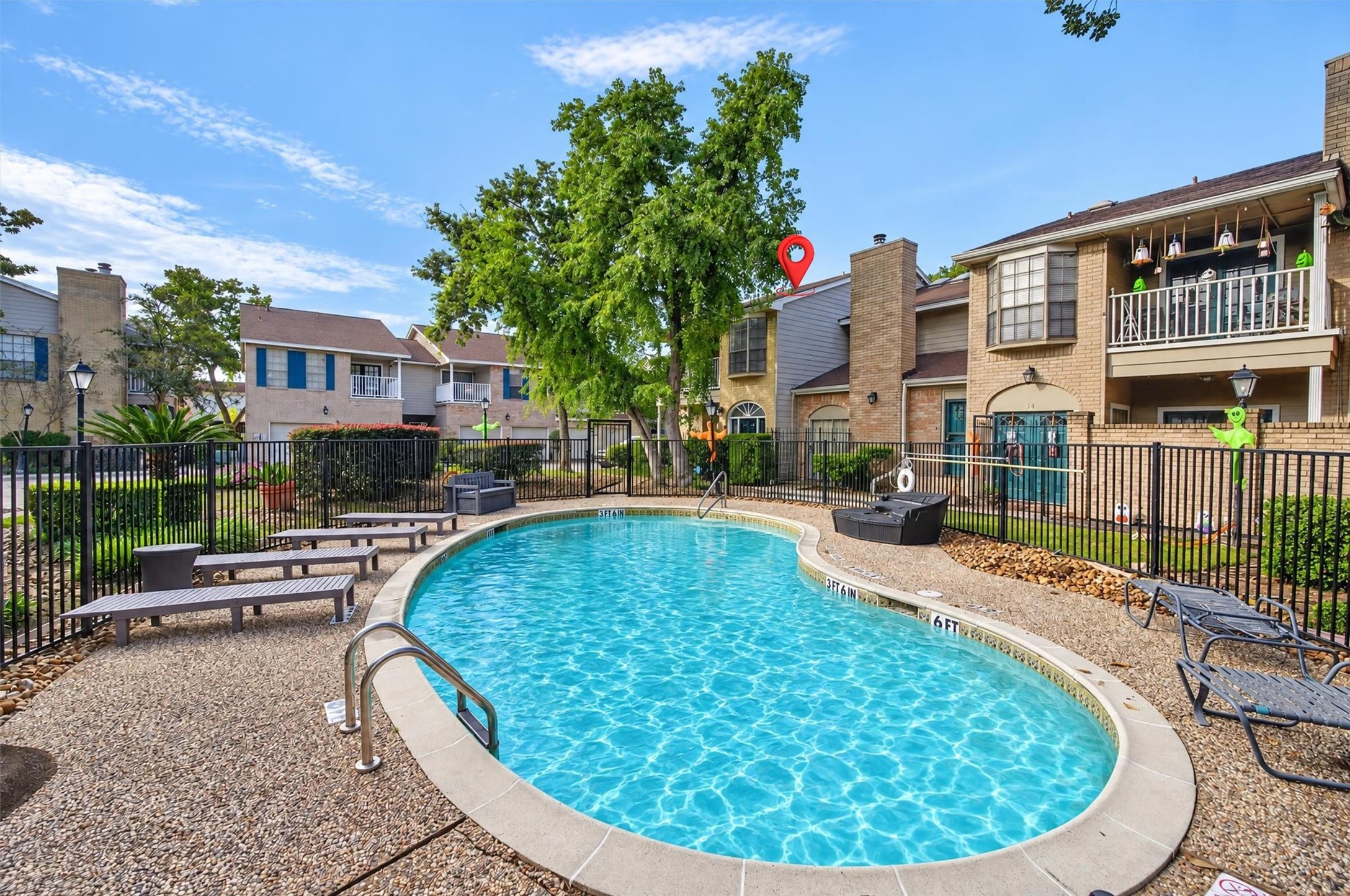 Community pool surrounded by mature trees and landscaped gathering areas.
