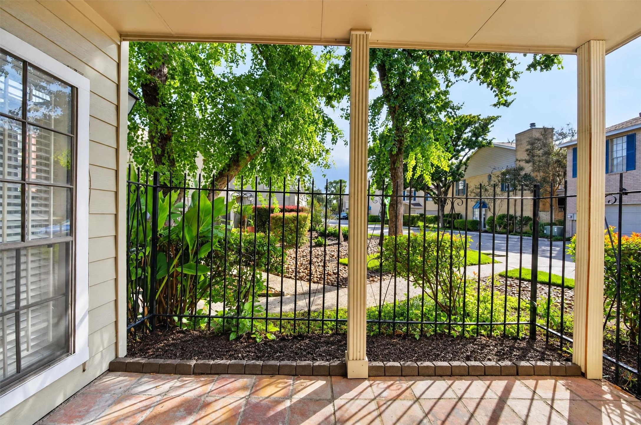 Covered, fenced patio overlooking landscaped grounds and mature trees.