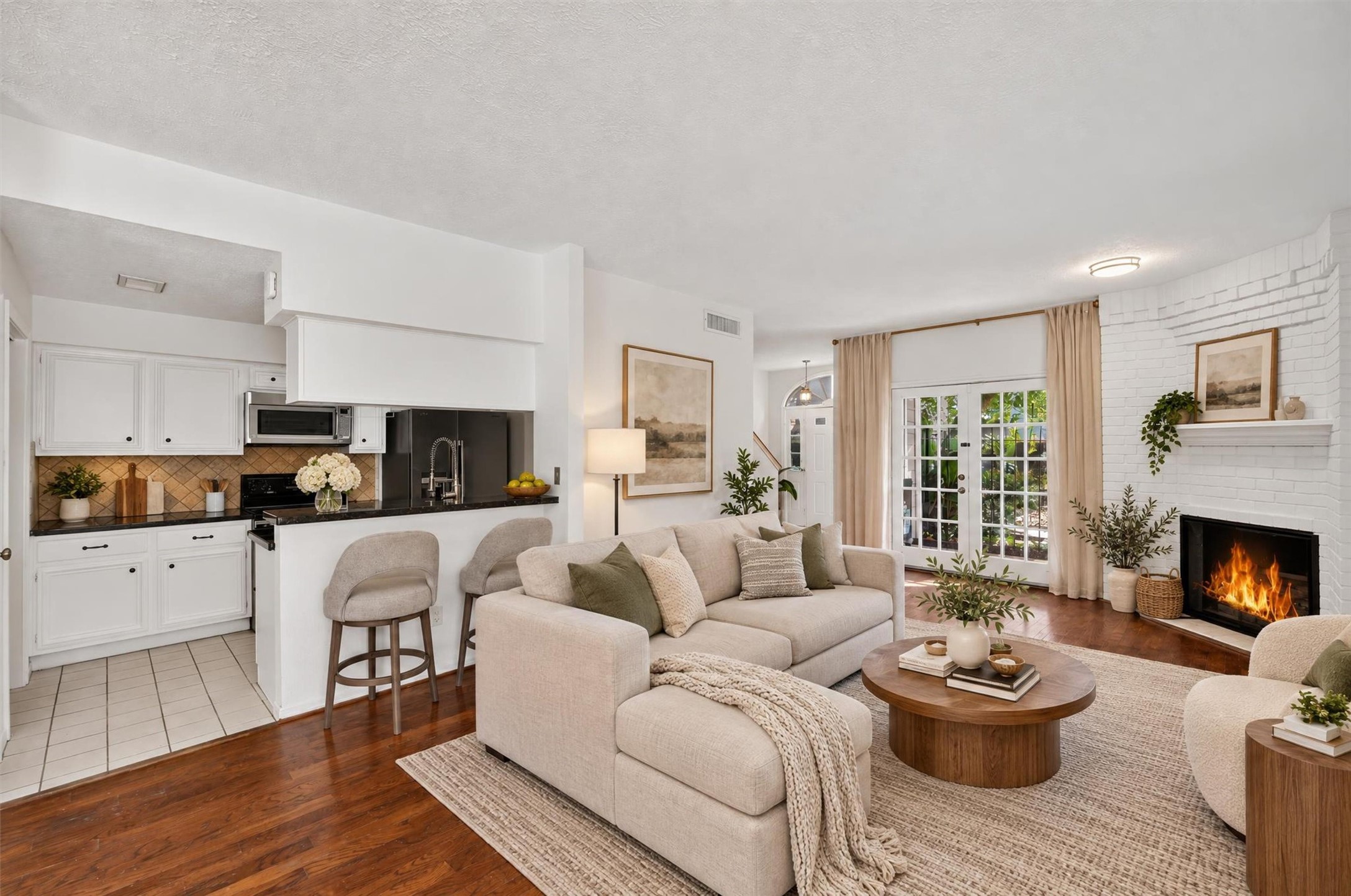 Open living area with a fireplace, breakfast bar, and French doors leading to the patio. Virtually staged.