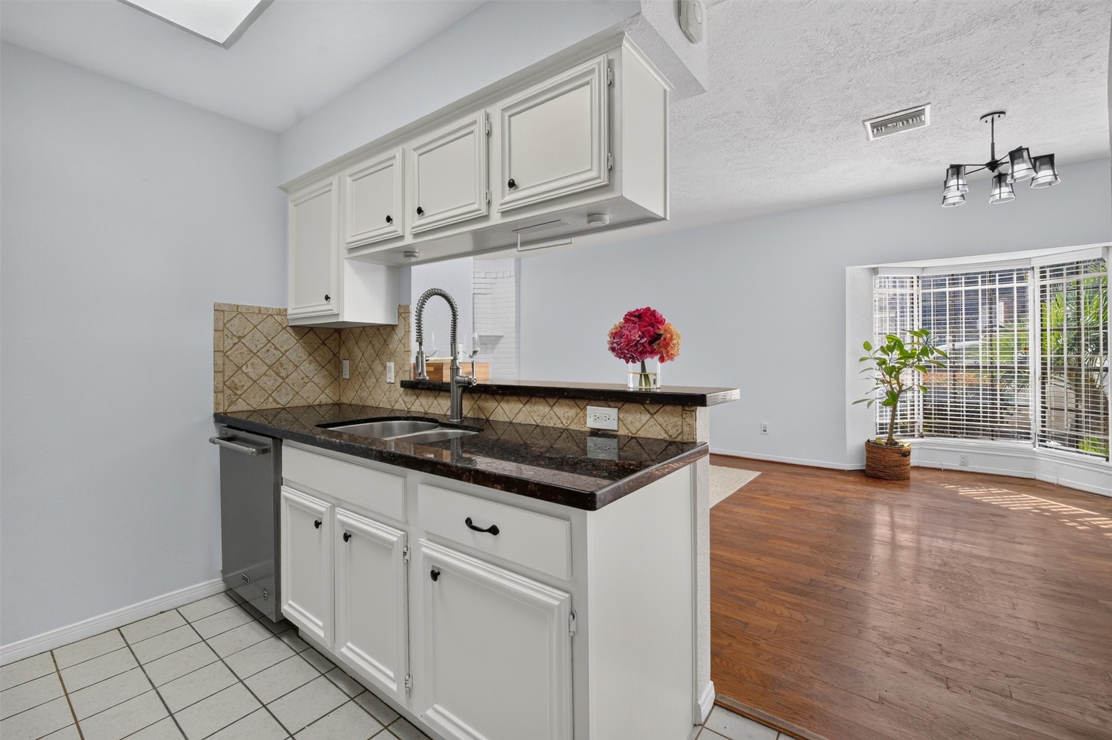 White cabinetry and dark countertops complement the kitchen's open connection to the dining area.