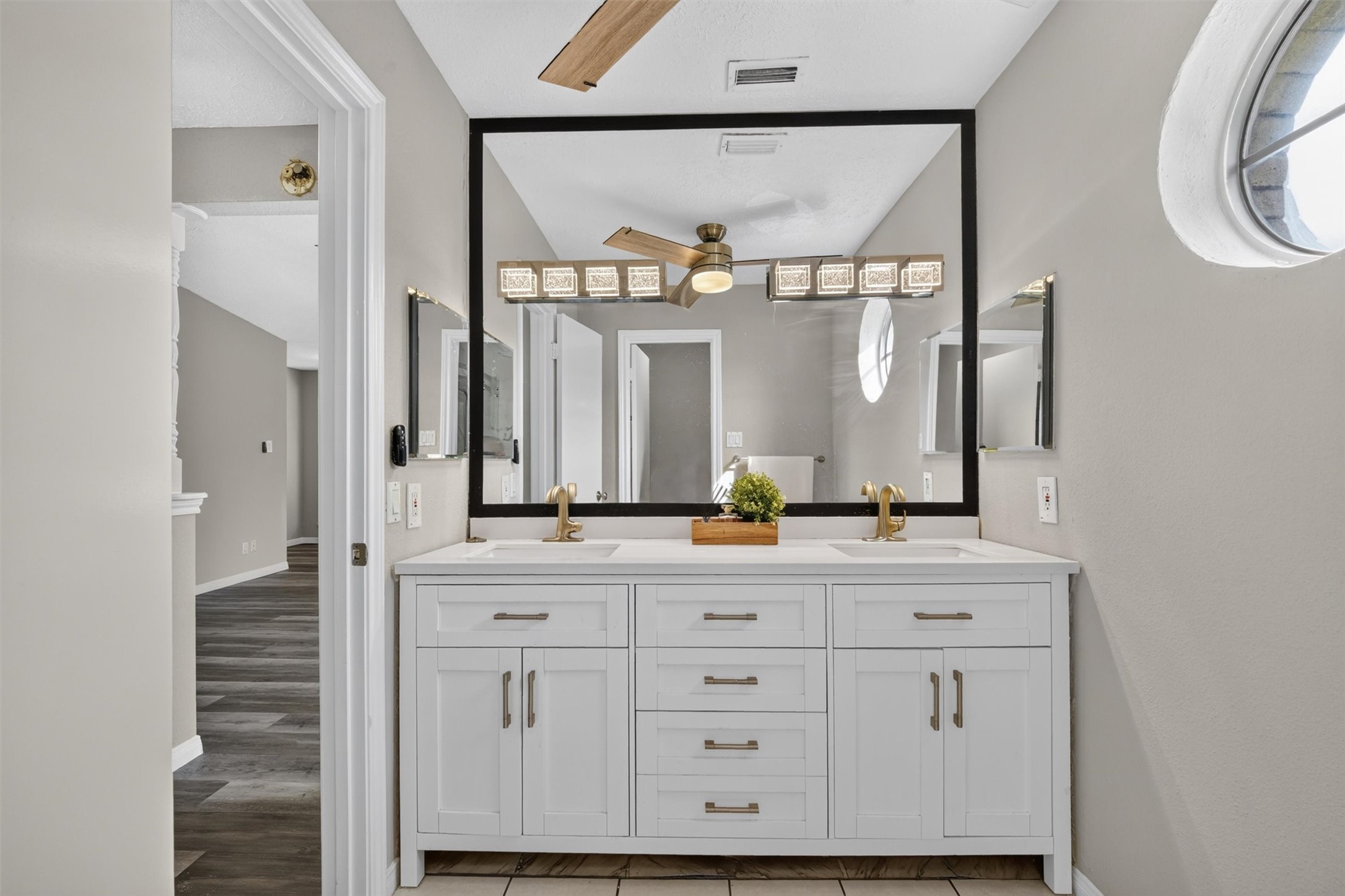 Updated primary bathroom vanity featuring dual sinks, a spacious countertop, a large framed mirror, and ample cabinet storage.