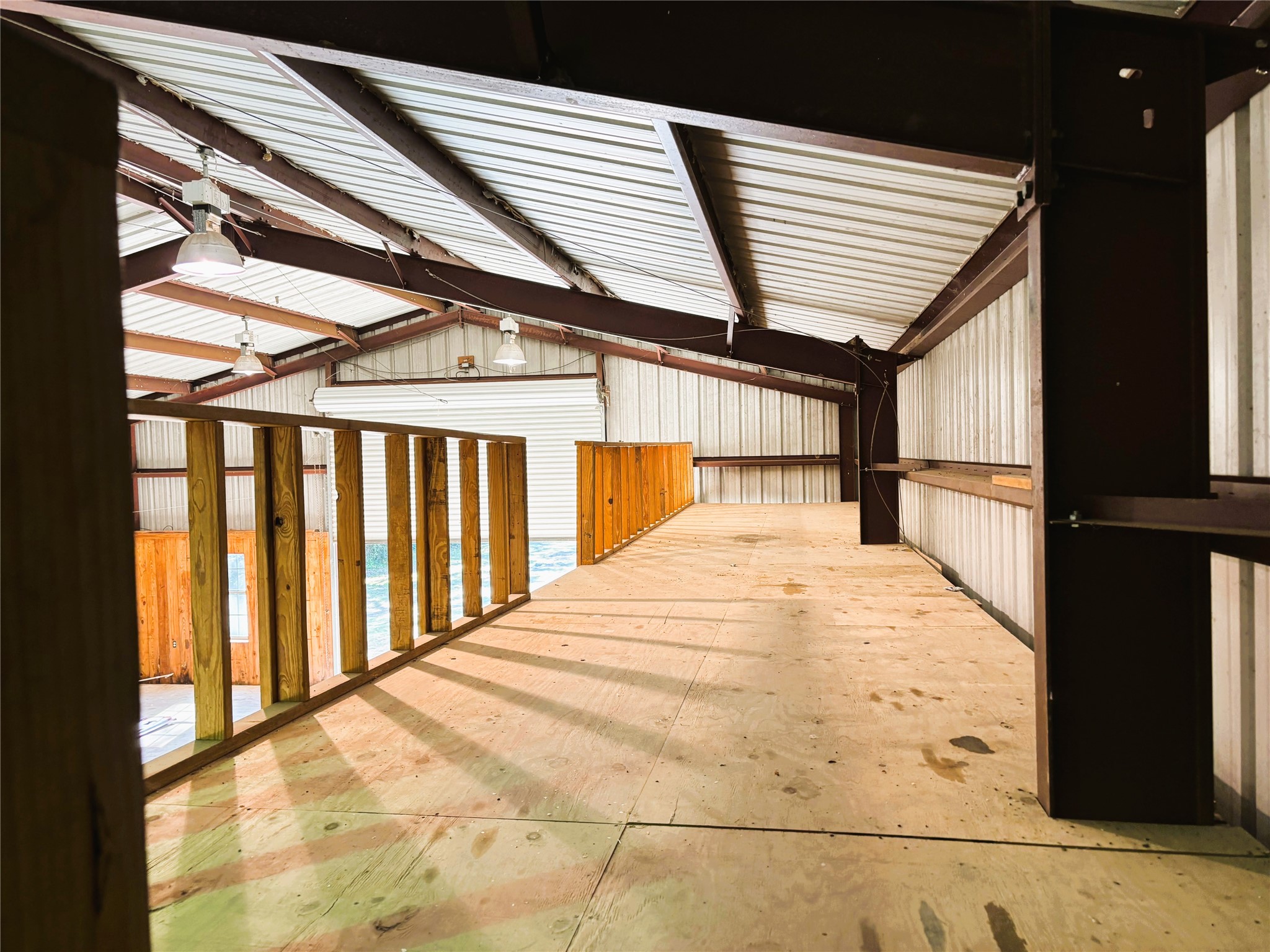 Spacious interior with high ceilings and natural light, featuring a sturdy wooden mezzanine perfect for storage or versatile use.
