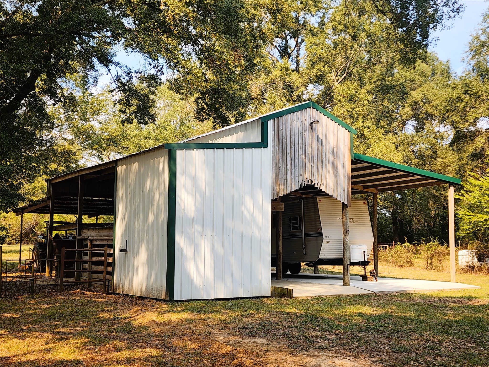 Spacious barn with covered RV storage, nestled among mature trees for ample shade and privacy.
