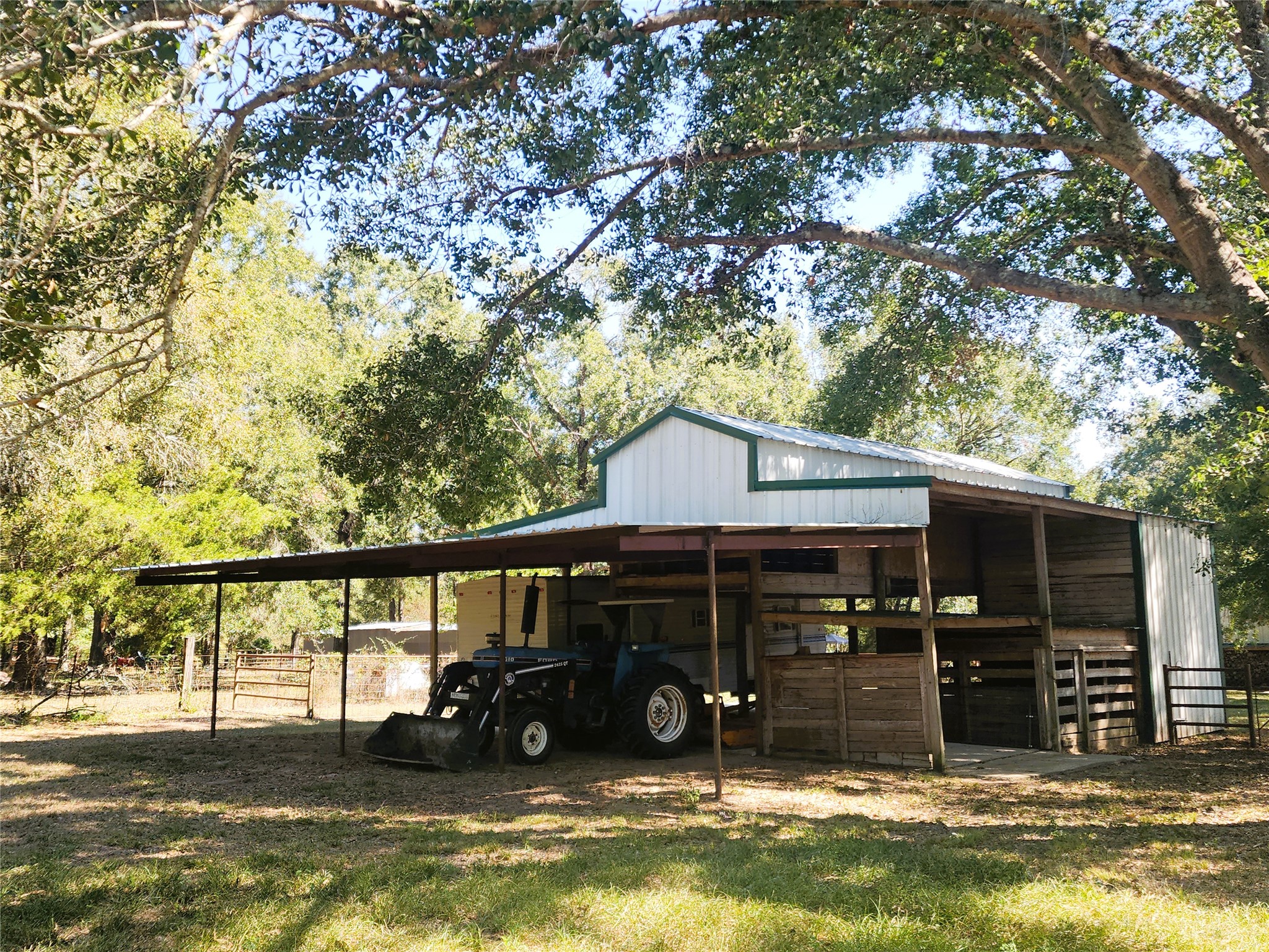 Charming rural barn with ample storage space, nestled under mature trees, perfect for agricultural use or equipment storage.