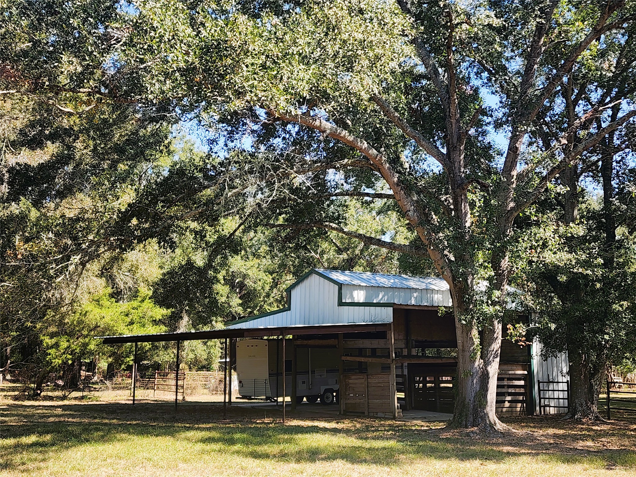 Charming rural property featuring a spacious 36'x36' barn with a 20'x36' lean-to set amidst lush, mature trees, offering ample shade and a serene natural setting.