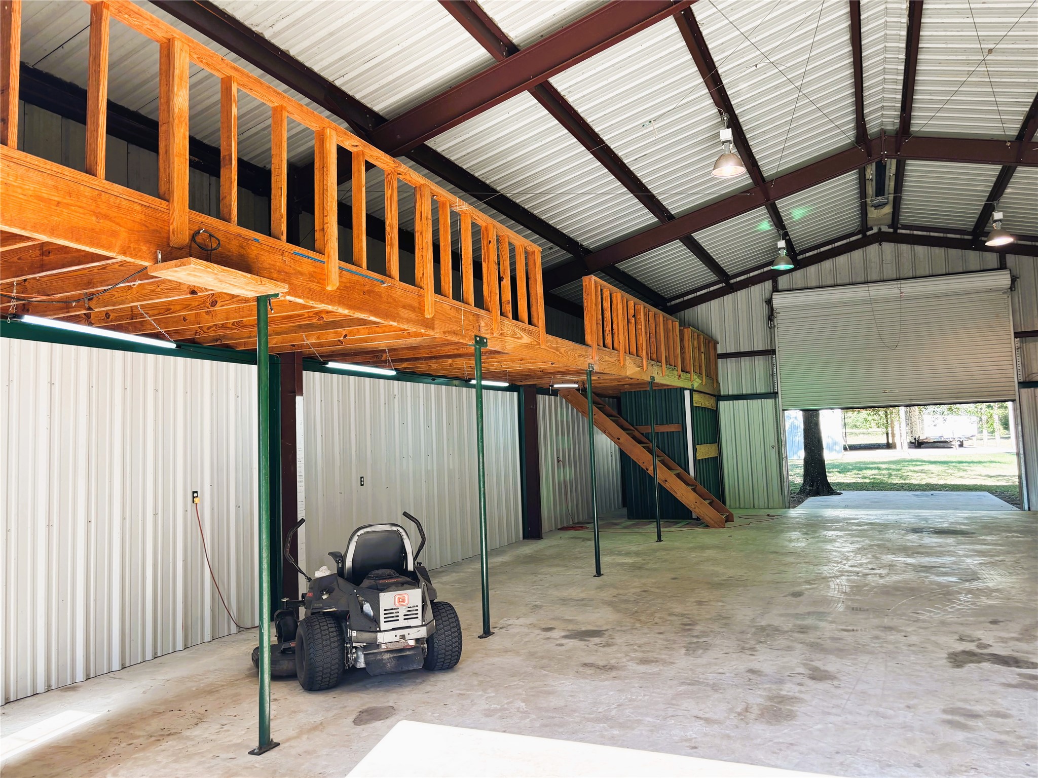 Spacious metal workshop with high ceilings, featuring a wooden loft the entire length of the building.