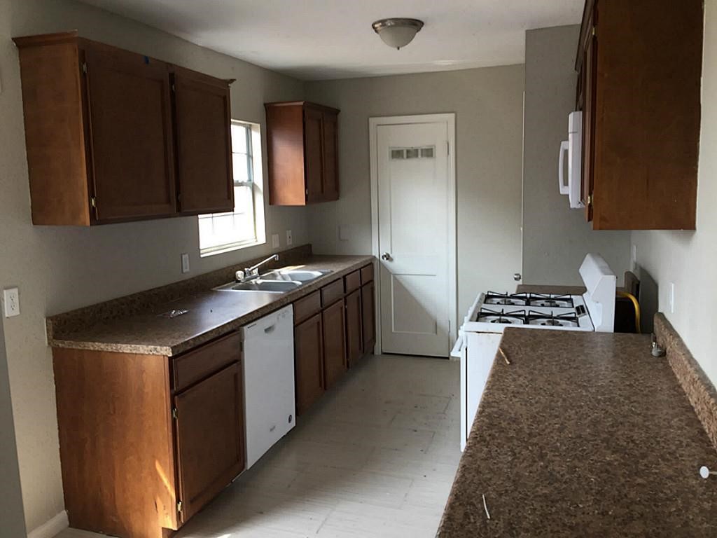 Kitchen with ample natural light, featuring rich wood cabinetry, durable countertops, and modern appliances for a functional cooking space.