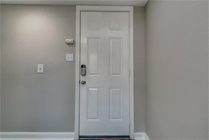 Entryway featuring a modern white door with a sleek keypad lock, set against neutral-toned walls for a welcoming ambiance.