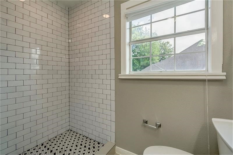 Classic subway-tiled shower and a window with a picturesque view, allowing natural light to brighten the space.