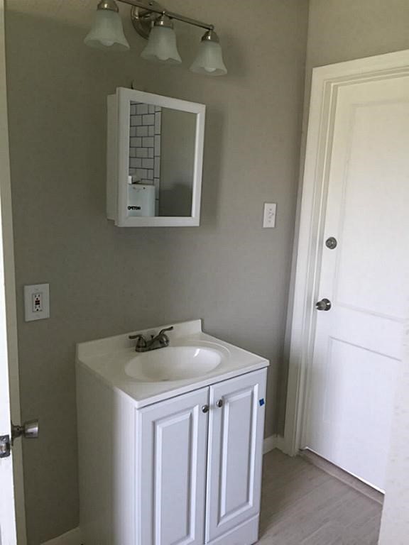 Bathroom features a sleek white vanity with ample storage, complemented by a modern mirror cabinet and elegant light fixture.