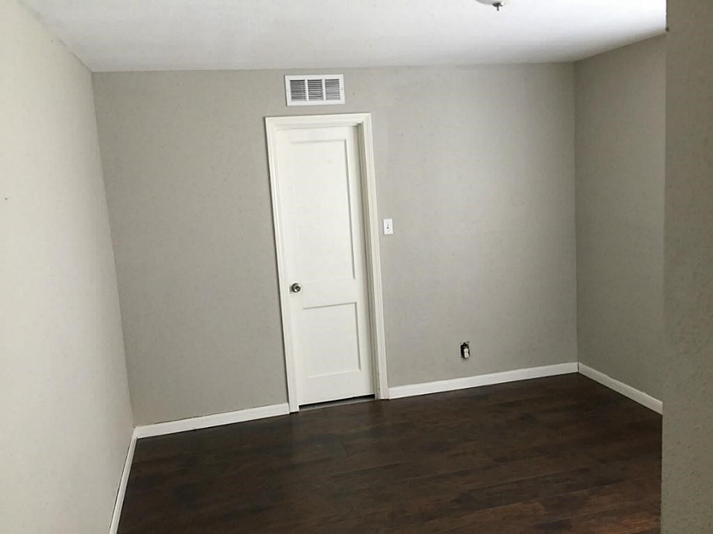 Room with neutral walls and rich, dark hardwood flooring, offering a clean slate for personalization.