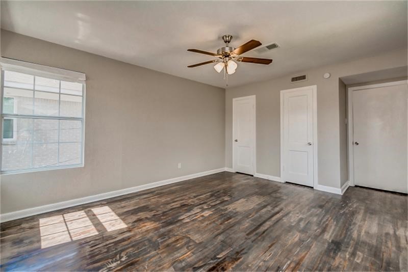 Sleek hardwood floors, a ceiling fan for comfort, and ample natural light streaming through a large window.