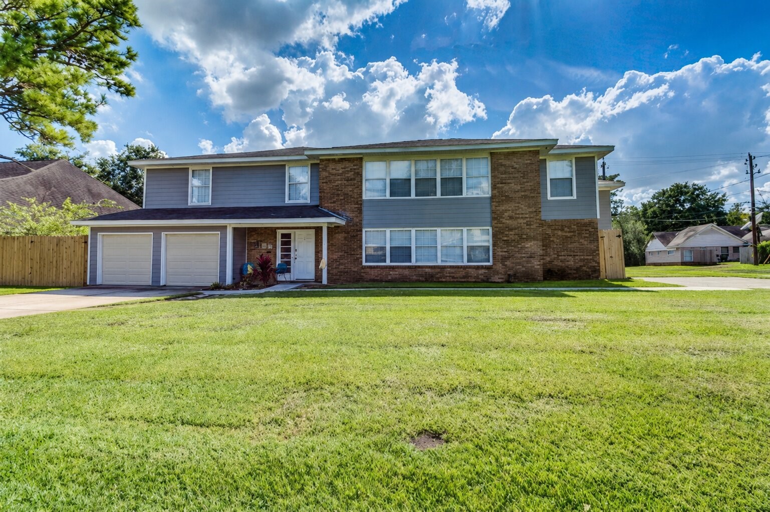 Two-story home with a blend of brick and siding, featuring a double garage and a well-maintained front lawn, perfect for family living.