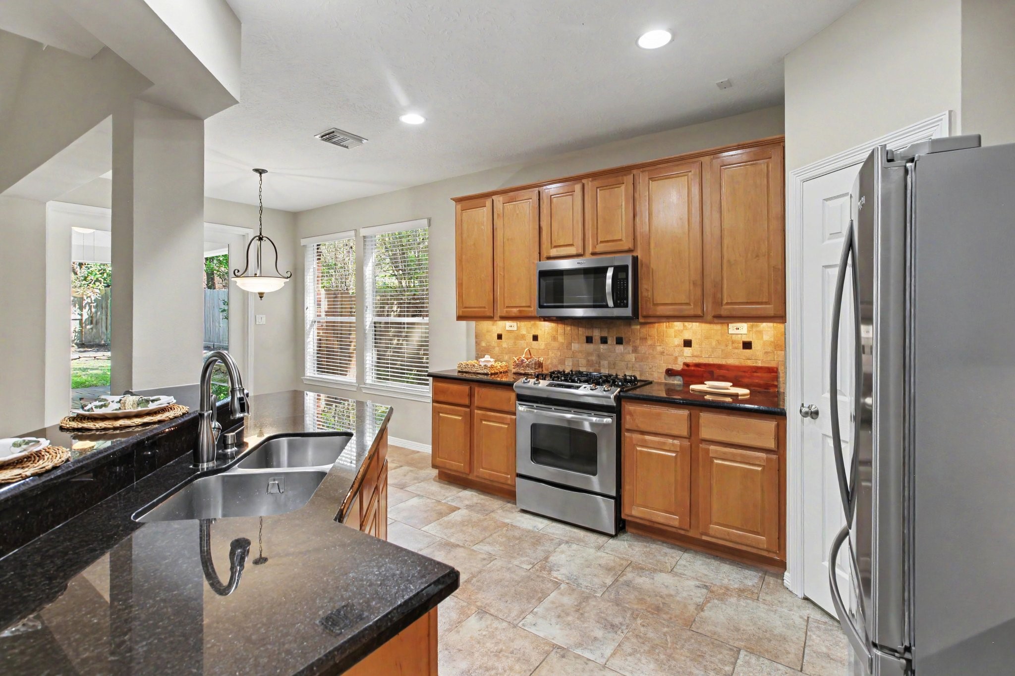 Gorgeous kitchen with granite countertops, stainless steel appliances including a gas range, microwave, dishwasher, and full size refrigerator, under cabinet lighting and an oversized pantry.