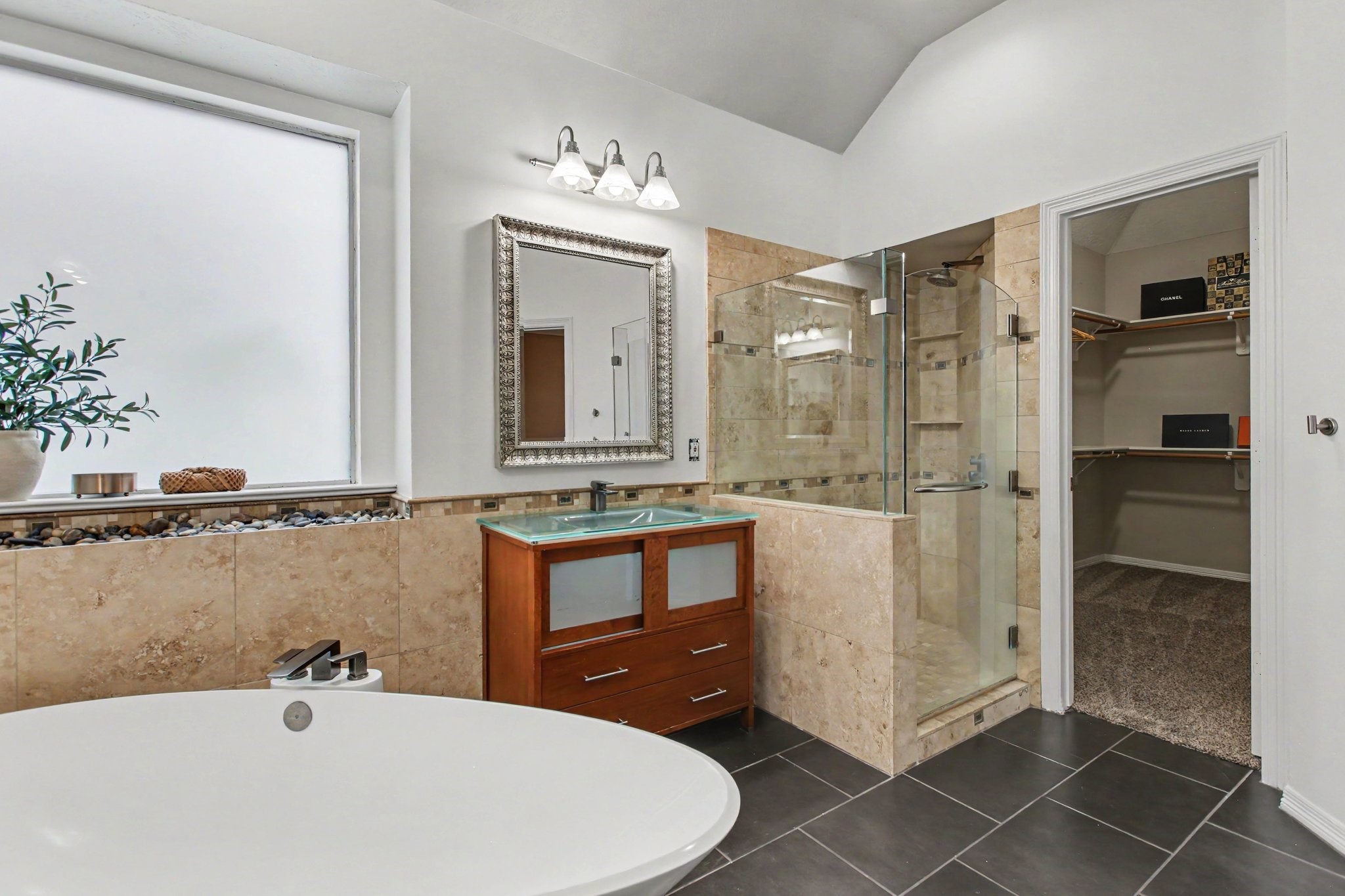 Another view of the ensuite bathroom showcasing the walk-in shower with rainfall shower head and built-in shelves and the oversized closet.