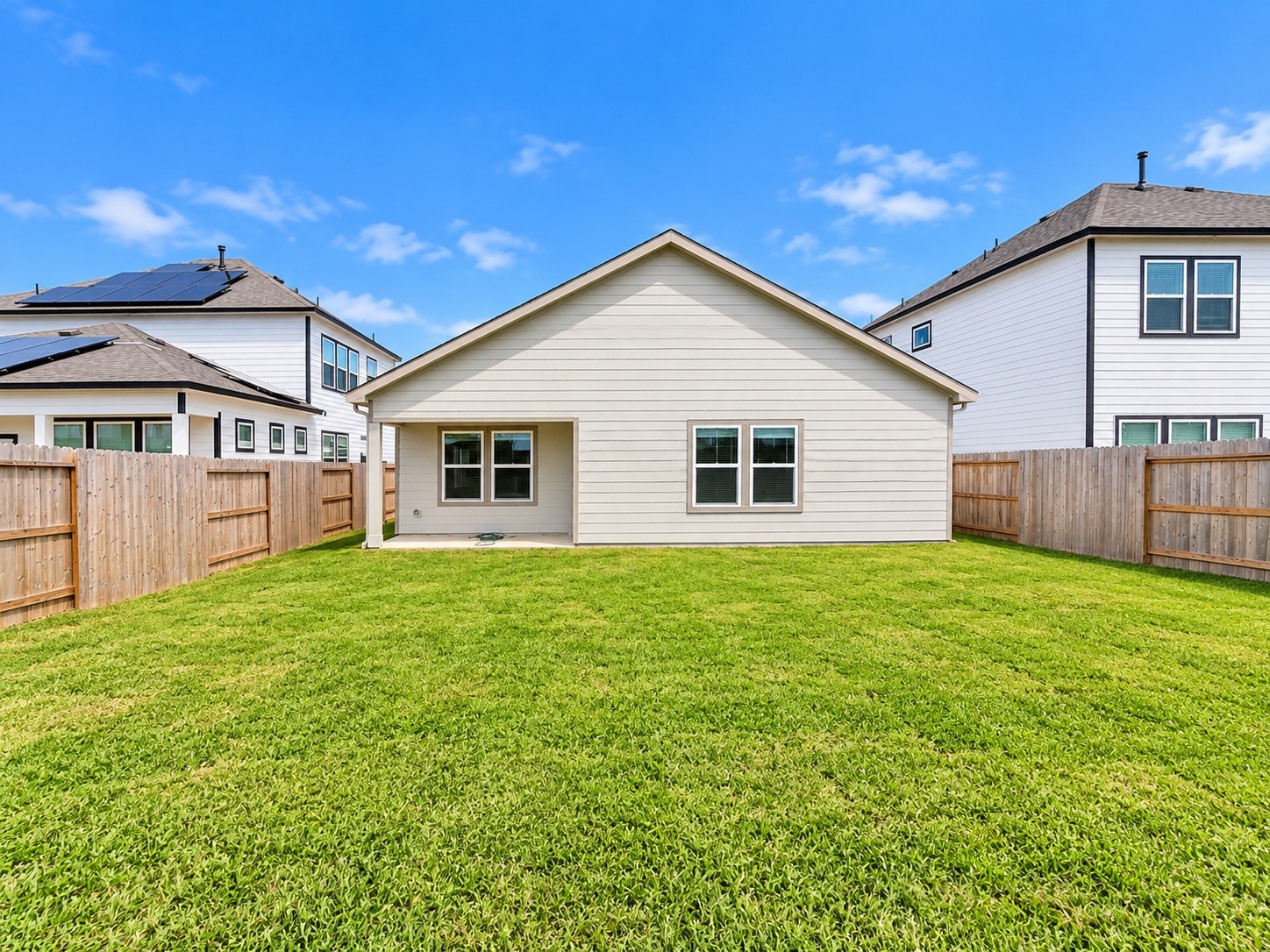 Spacious backyard with well-maintained lawn and a cozy covered patio, perfect for outdoor activities and relaxation.
