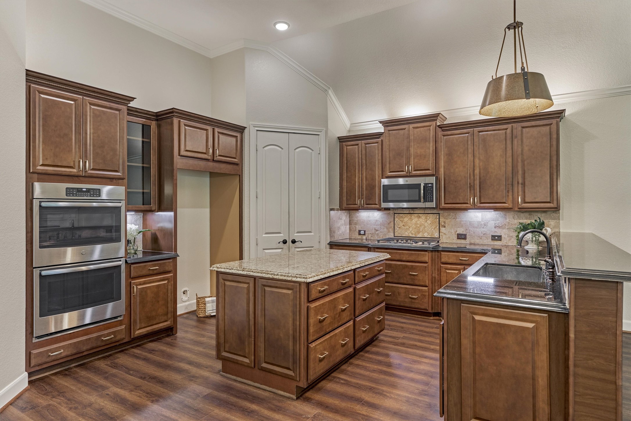 Chef's kitchen is optimally spacious with tons of cabinetry and counterspace, featuring a long dining bar that opens to the cozy den.