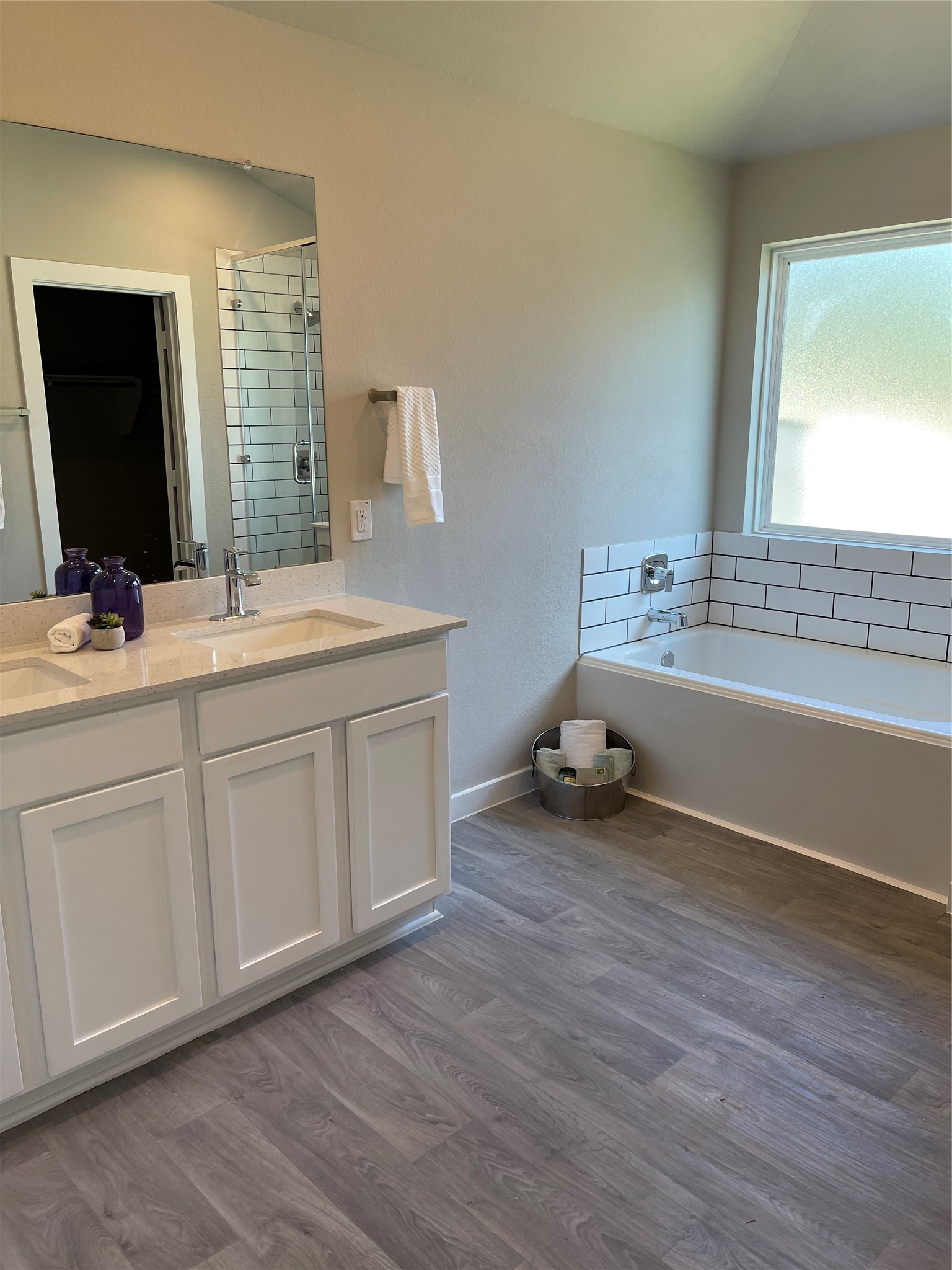 Bright and modern bathroom featuring a sleek double vanity, spacious soaking tub, and stylish subway tile accents. Bright and modern bathroom featuring a sleek double vanity, spacious soaking tub, and stylish subway tile accents.