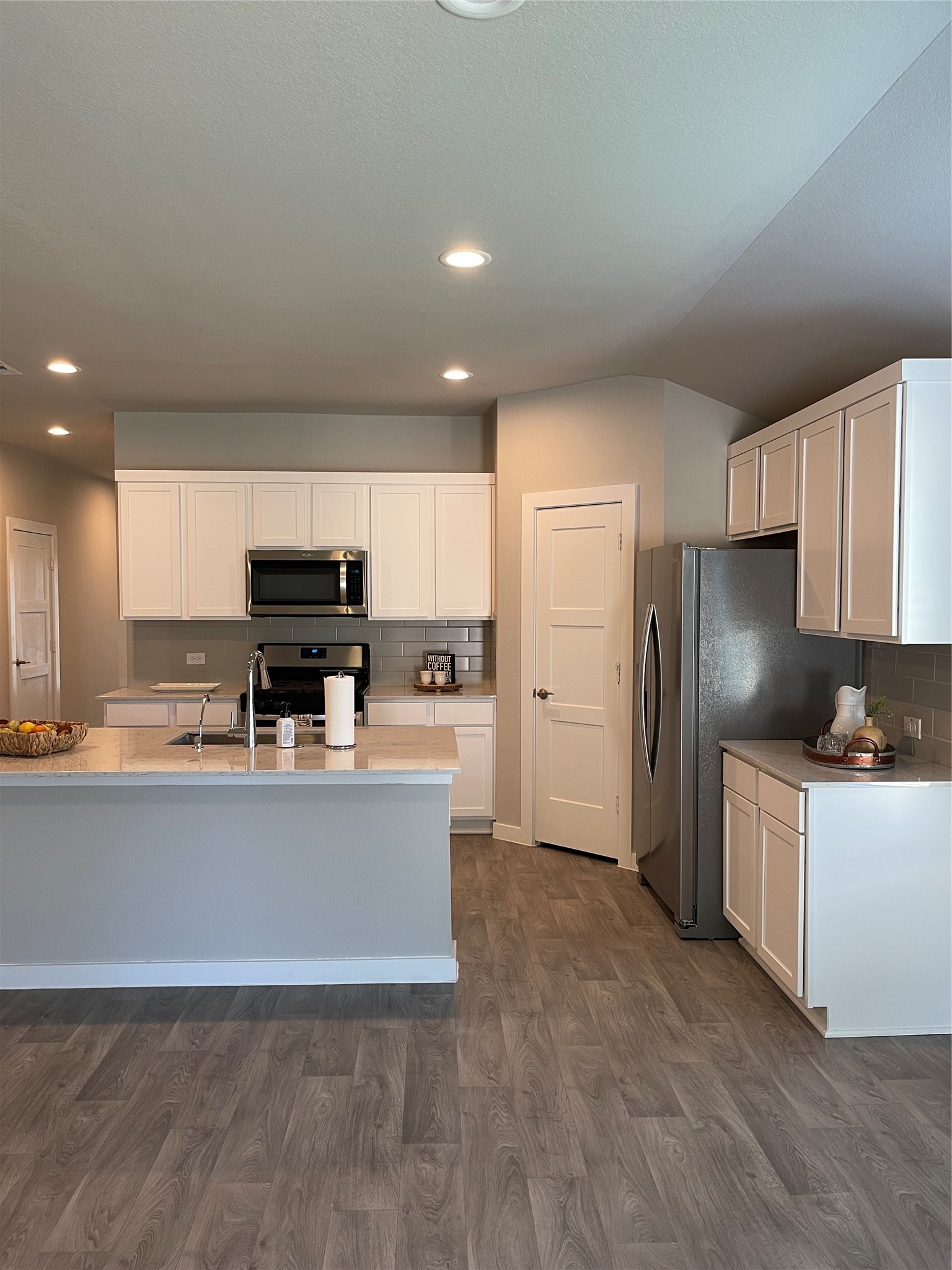 Modern kitchen with sleek white cabinetry, stainless steel appliances, and a spacious island, complemented by elegant vinyl plank flooring.