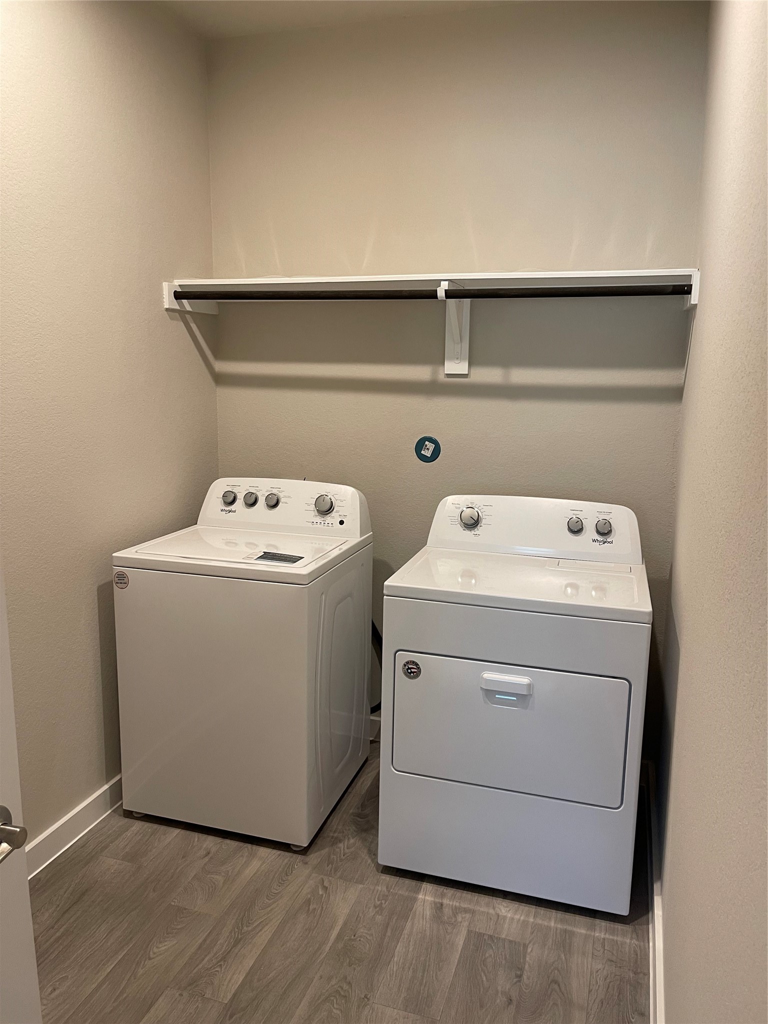 Convenient laundry room featuring a washer and dryer with overhead shelving for extra storage. Convenient laundry room featuring a washer and dryer with overhead shelving for extra storage.