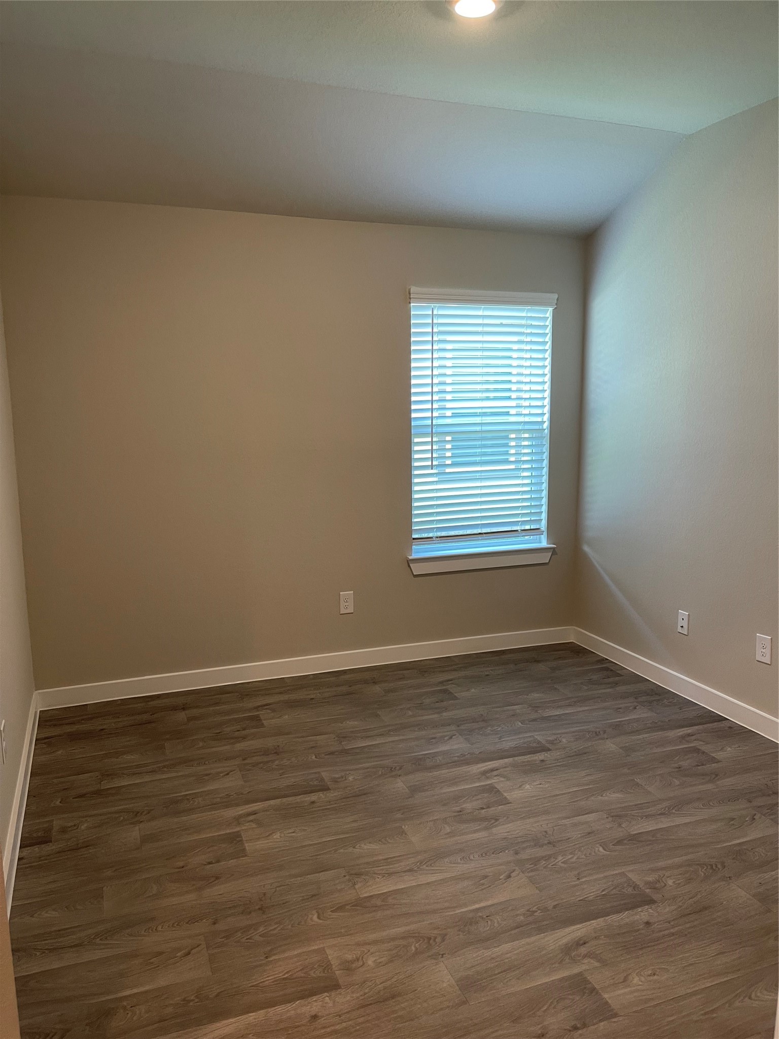 Cozy room with neutral walls, and a window allowing natural light to brighten the space.
