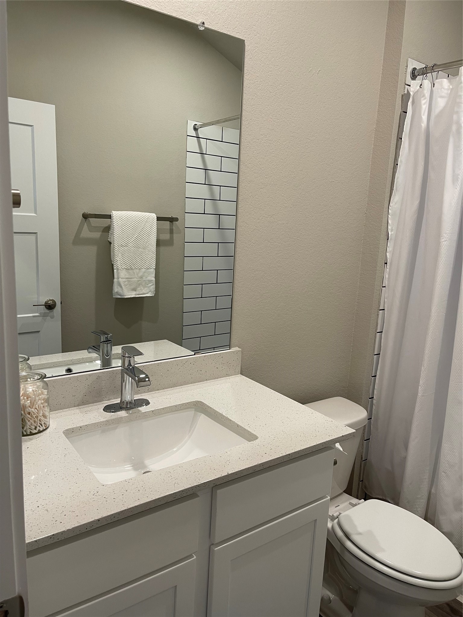 Modern bathroom with a sleek vanity, white countertop, and chrome fixtures, featuring a stylish subway tile shower and neutral tones for a clean, inviting look.