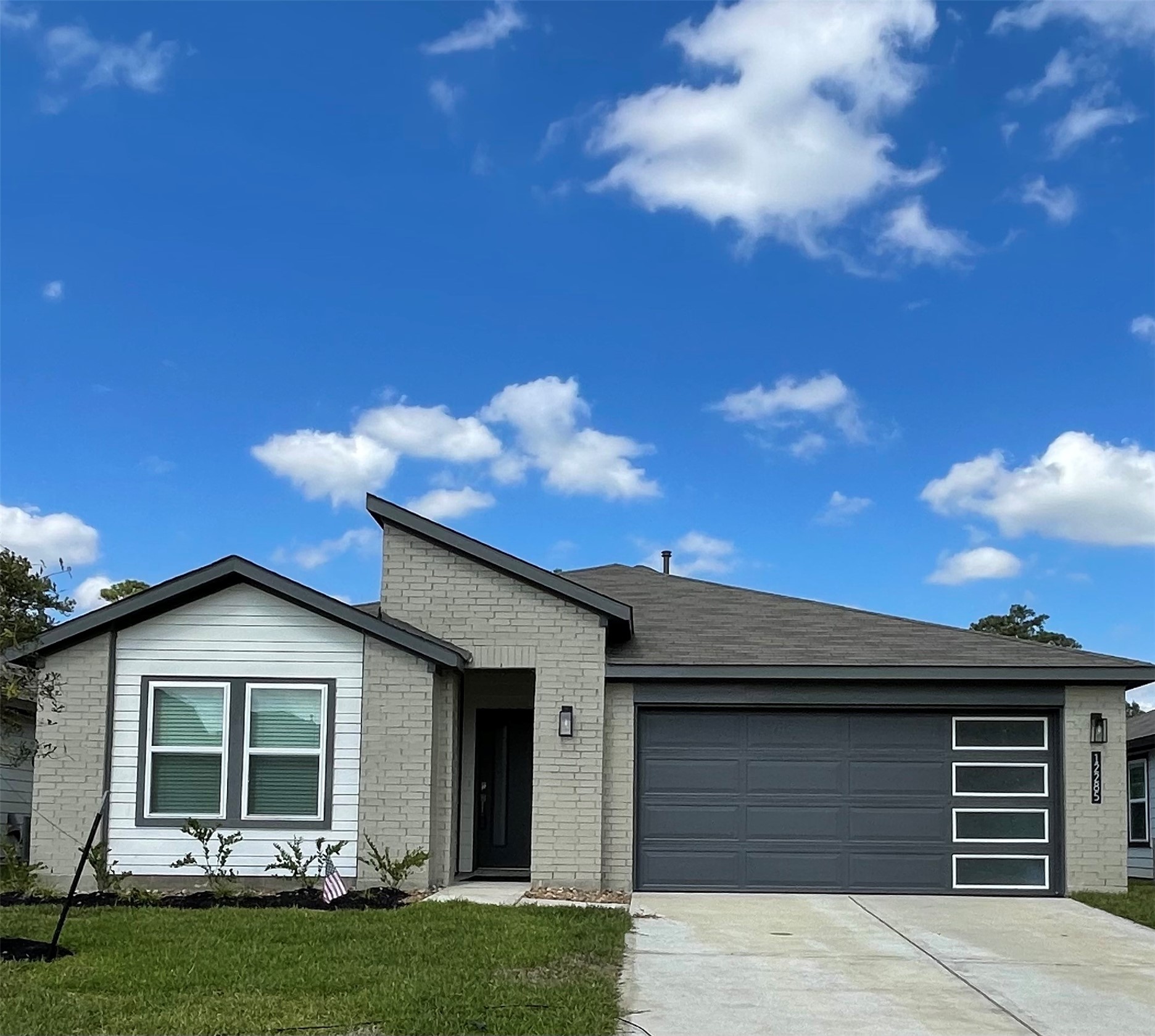 Modern single-story home with a sleek gray facade, stylish garage door, and beautiful front lawn.