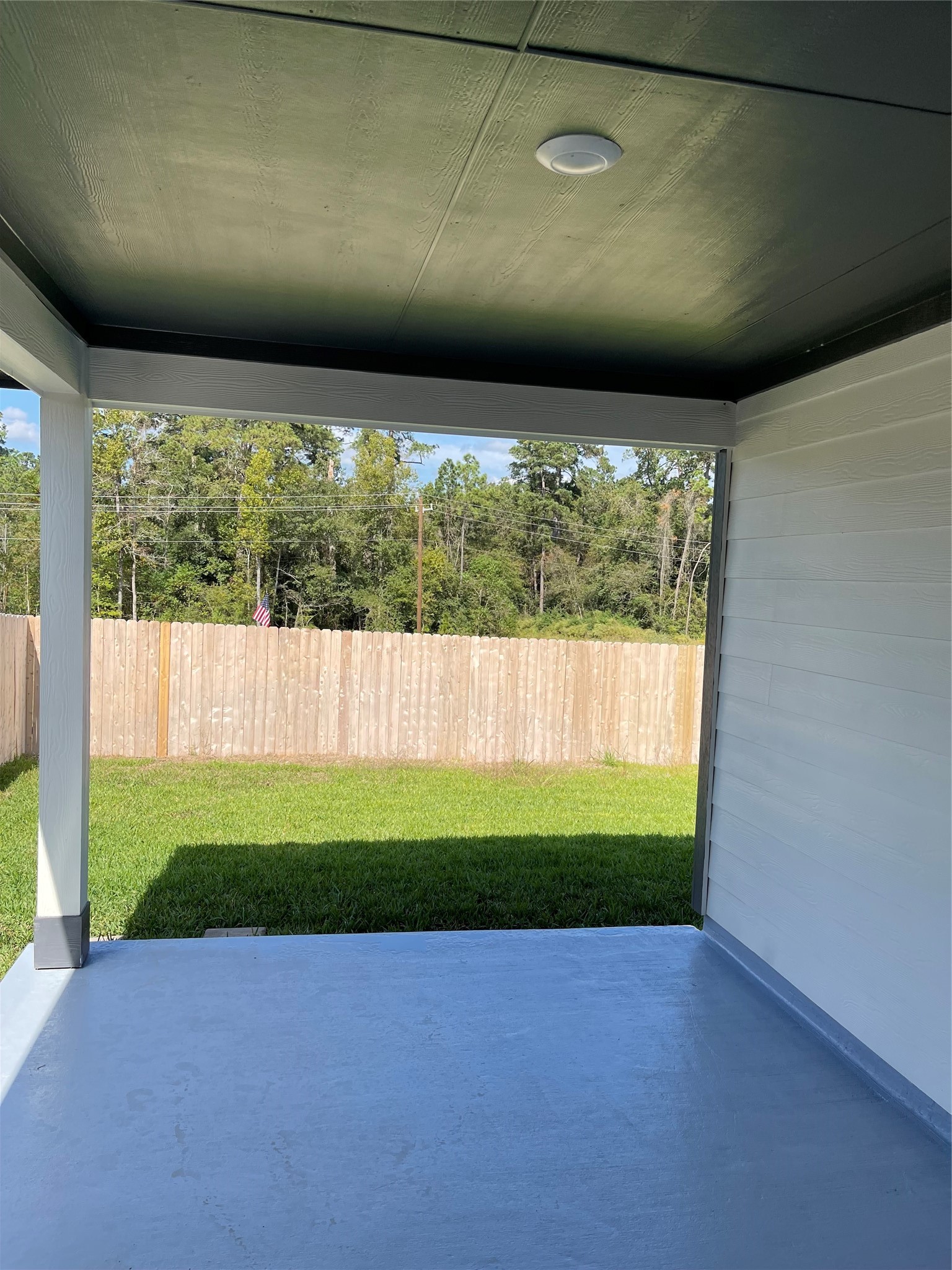Enjoy a covered patio with views of a spacious, fenced backyard, providing a serene outdoor retreat.
