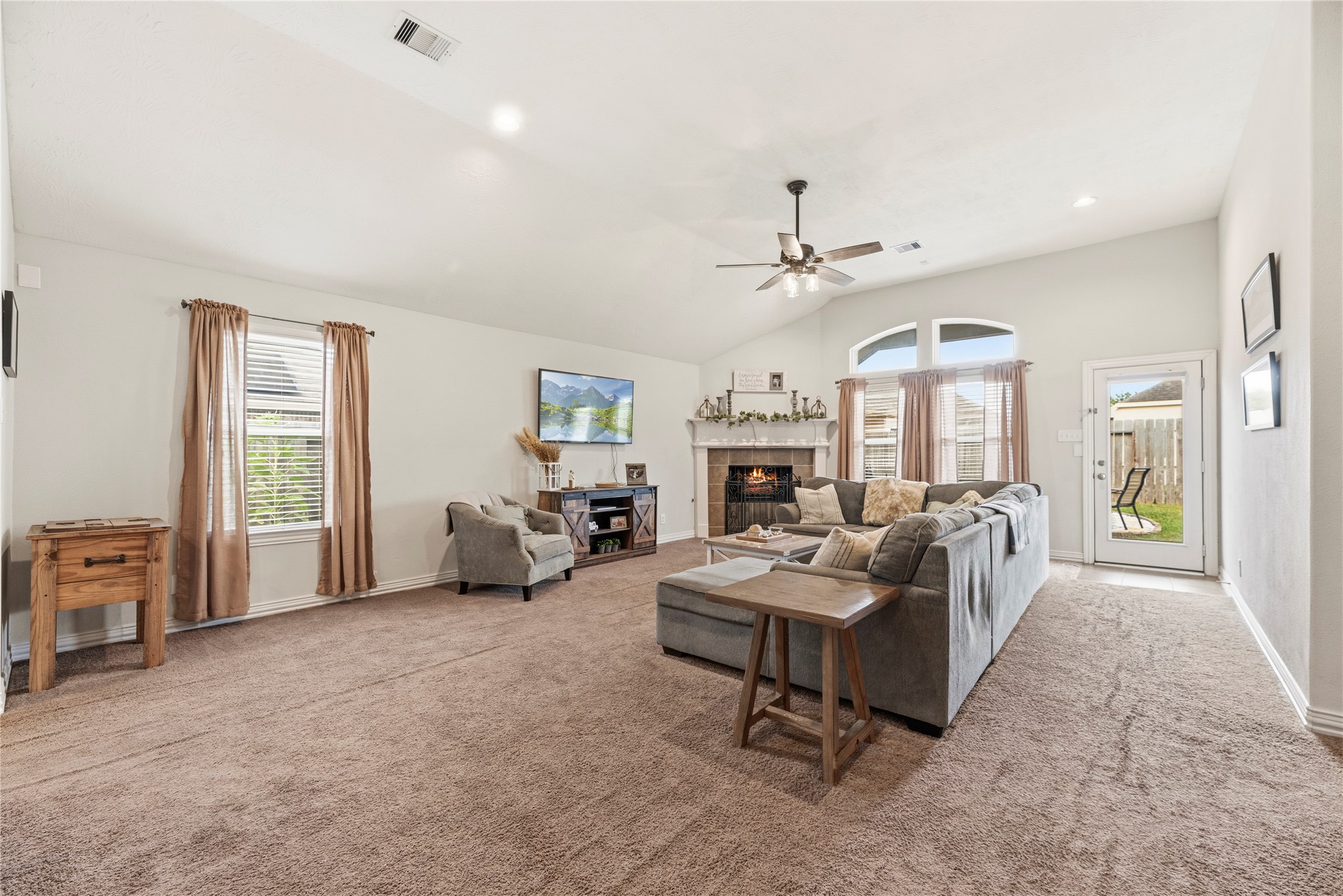 Spacious family room offers plush carpet, ceiling fan and a corner fireplace.