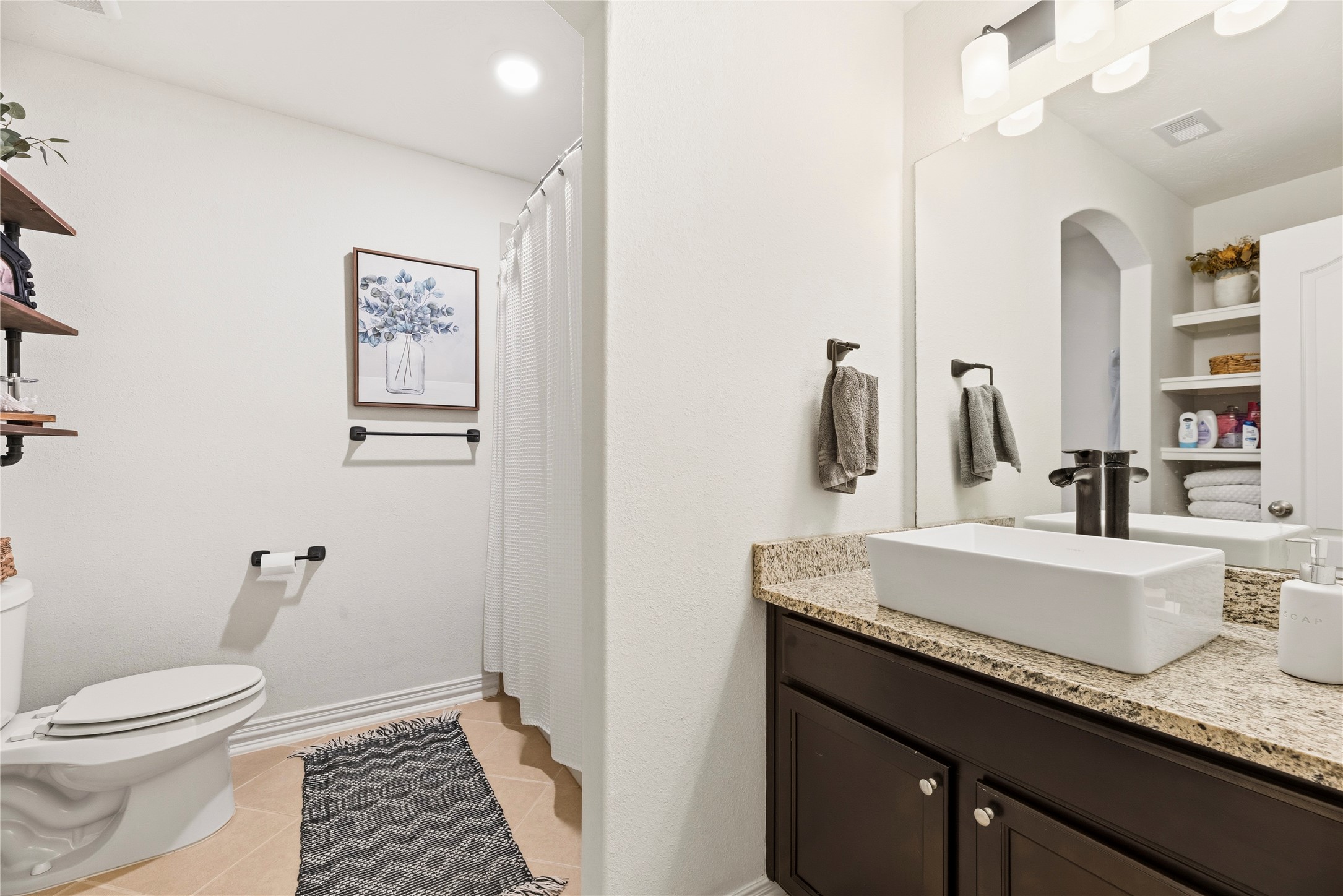 Full guest bathroom with built-in shelving and a tub/shower combination.