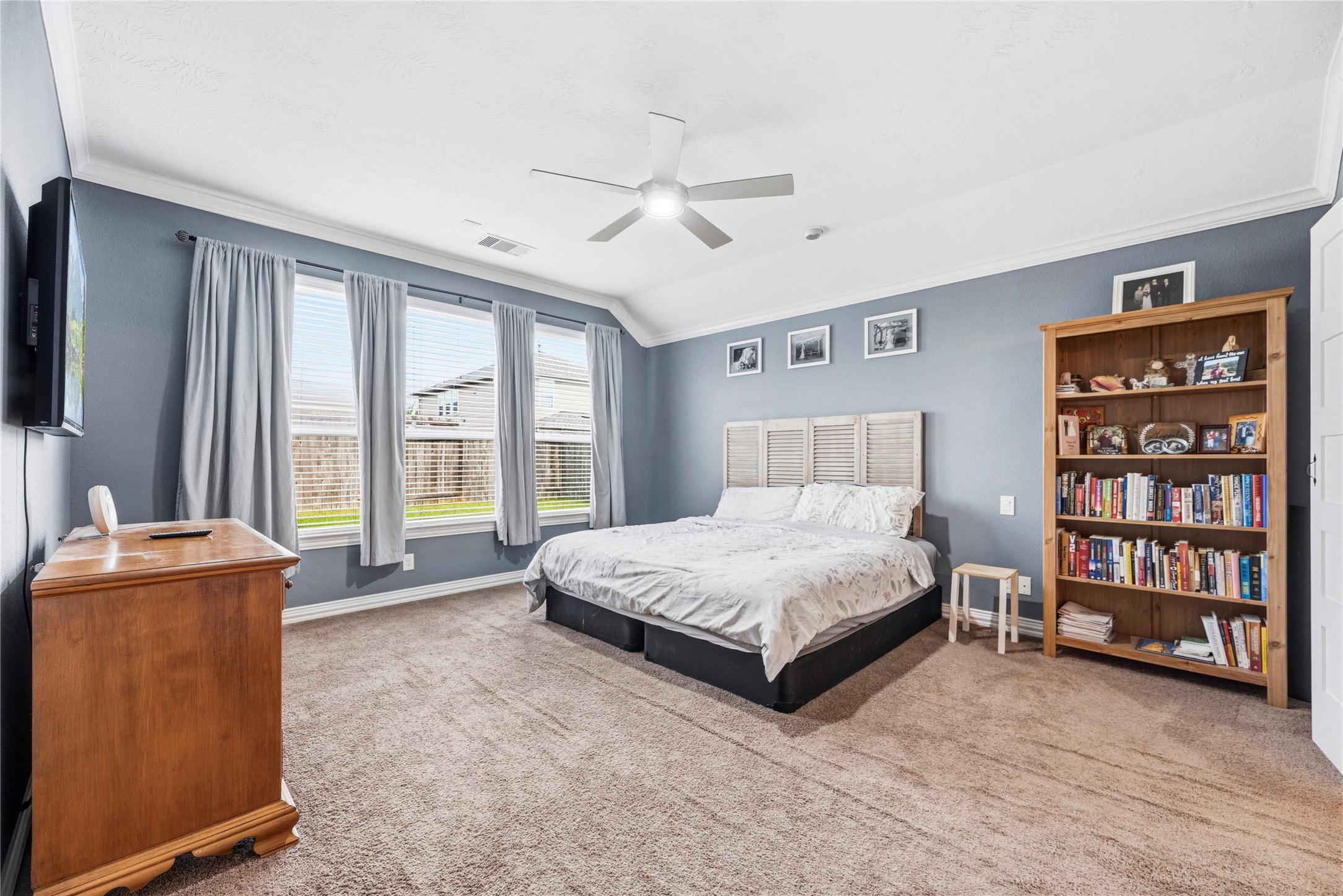 Large primary retreat boasts a high ceiling, ceiling fan, crown molding, en-suite bathroom and great backyard views.