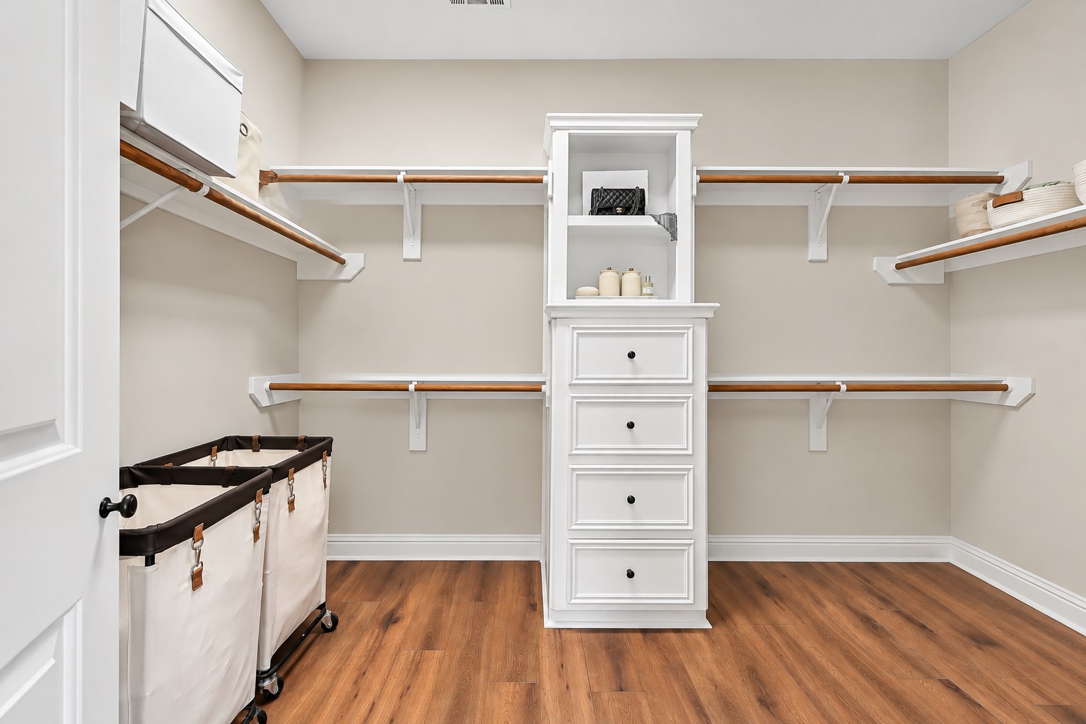 An oversized primary walk-in closet provides extensive hanging and storage space with built-in shelving, double hanging rods and a center drawer tower. Its generous dimensions offer plenty of room to keep clothing, shoes and accessories organized.