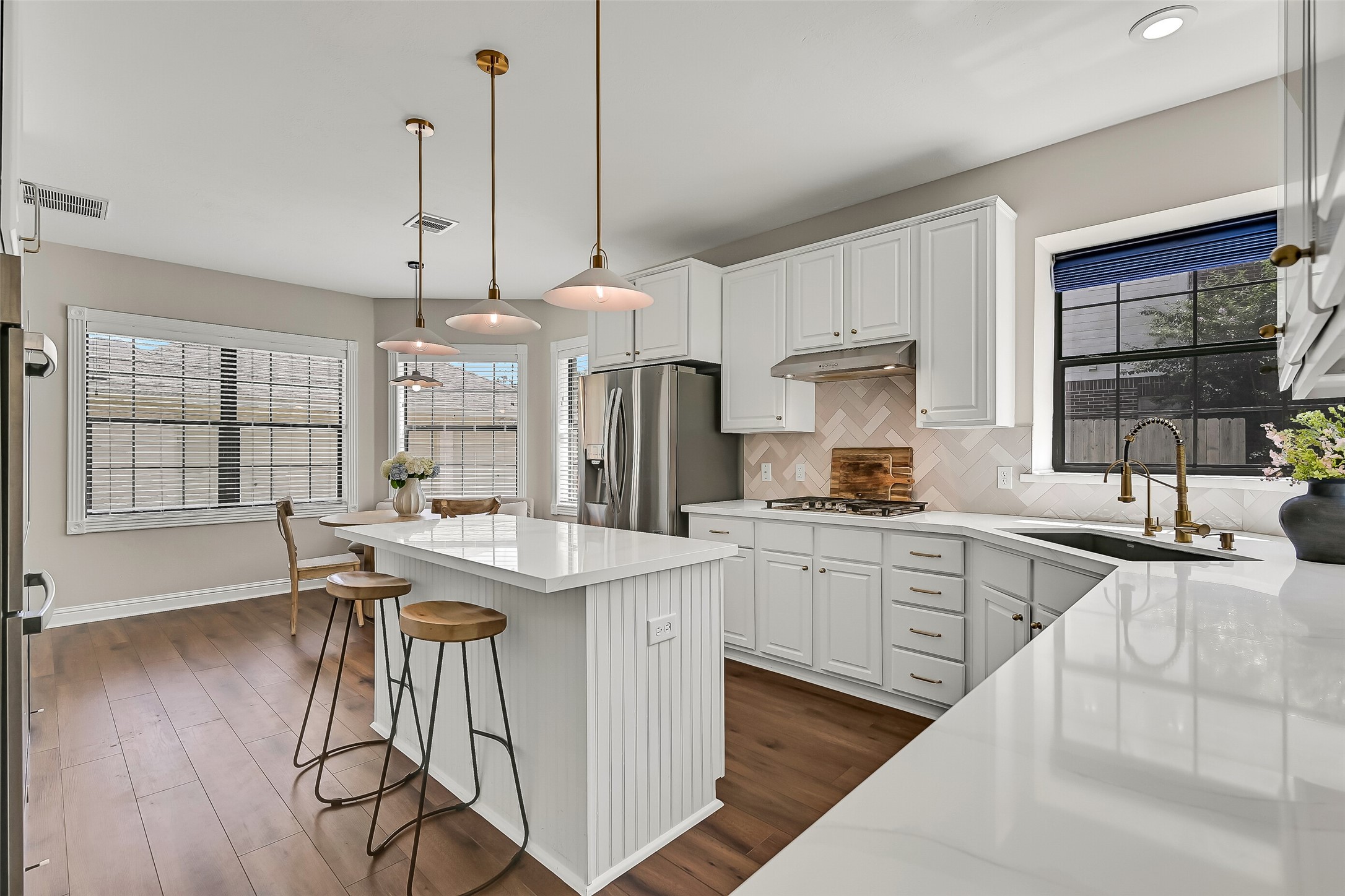 The island kitchen opens directly to a sunny breakfast area surrounded by windows. With abundant cabinetry, generous counter space, stainless appliances and plenty of room for casual dining, this inviting space serves as a natural hub of the home.