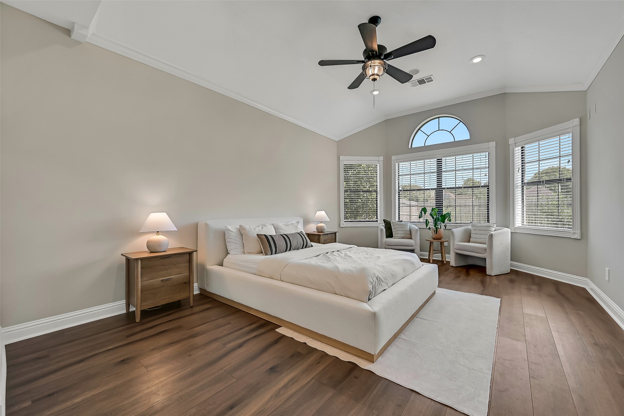 Privately situated on the first floor, the spacious primary retreat features a vaulted ceiling, luxury vinyl plank flooring and a generous bank of windows topped by an arched transom, filling the room with beautiful natural light.