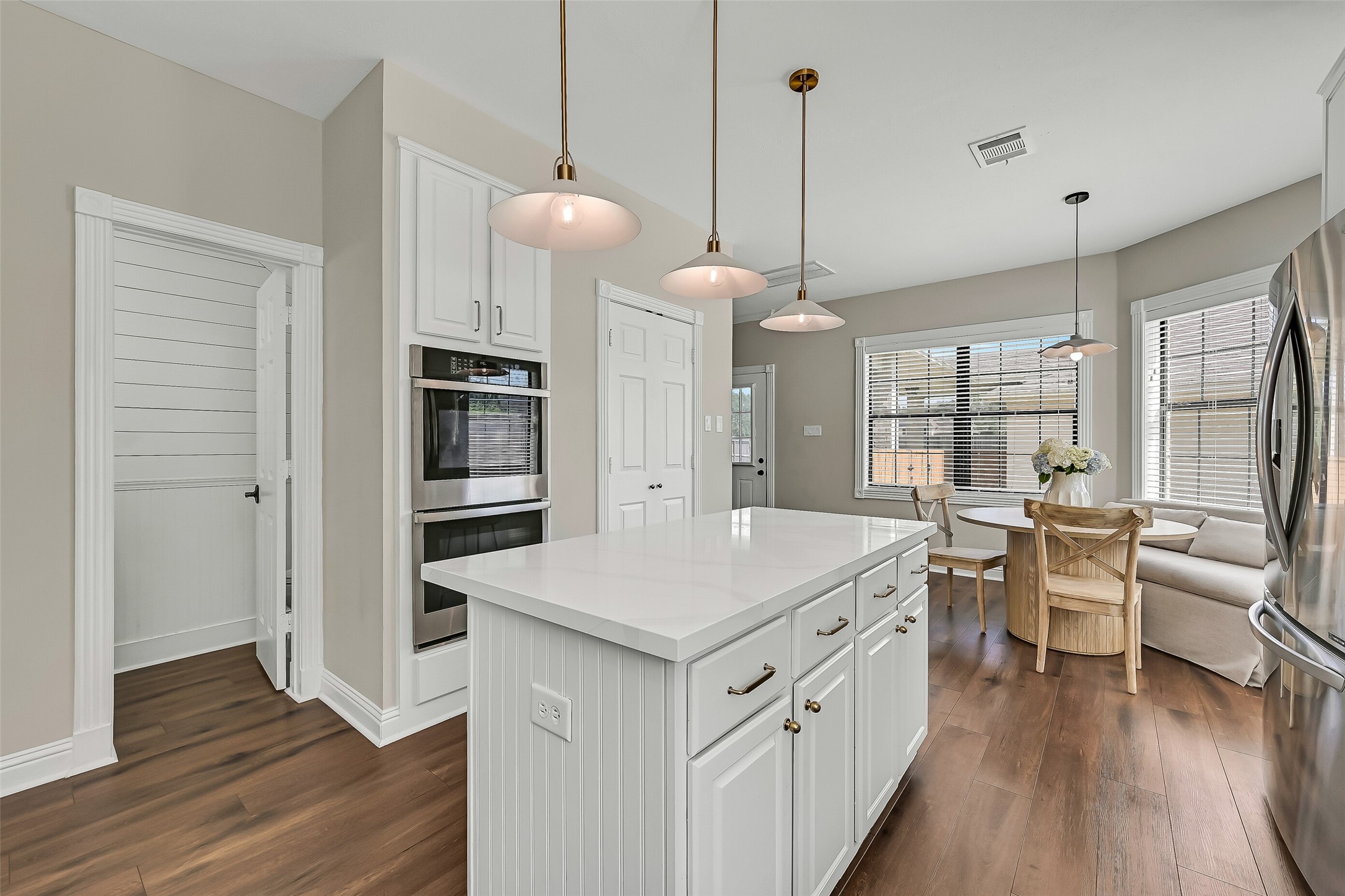 Designed with both style and function in mind, the kitchen boasts stainless steel appliances, double ovens, a gas cooktop with vent hood, quartzite countertops and extensive soft-close cabinetry. A window above the sink brings even more natural light into the space.