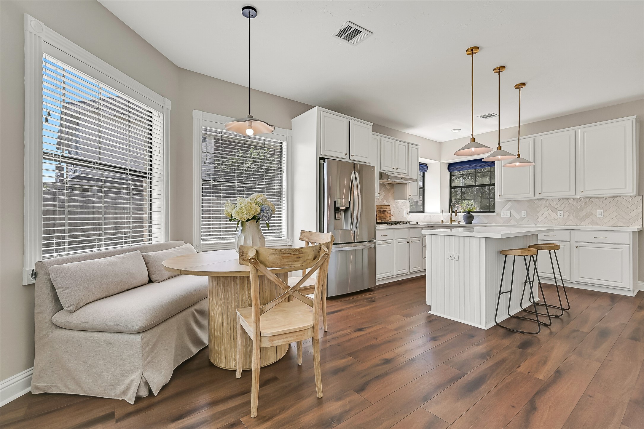 A wider perspective showcases the generous scale of the family room and its easy connection to the kitchen and breakfast area. The gas-log fireplace, built-in shelving, recessed lighting and wall of backyard-facing windows add both character and function.