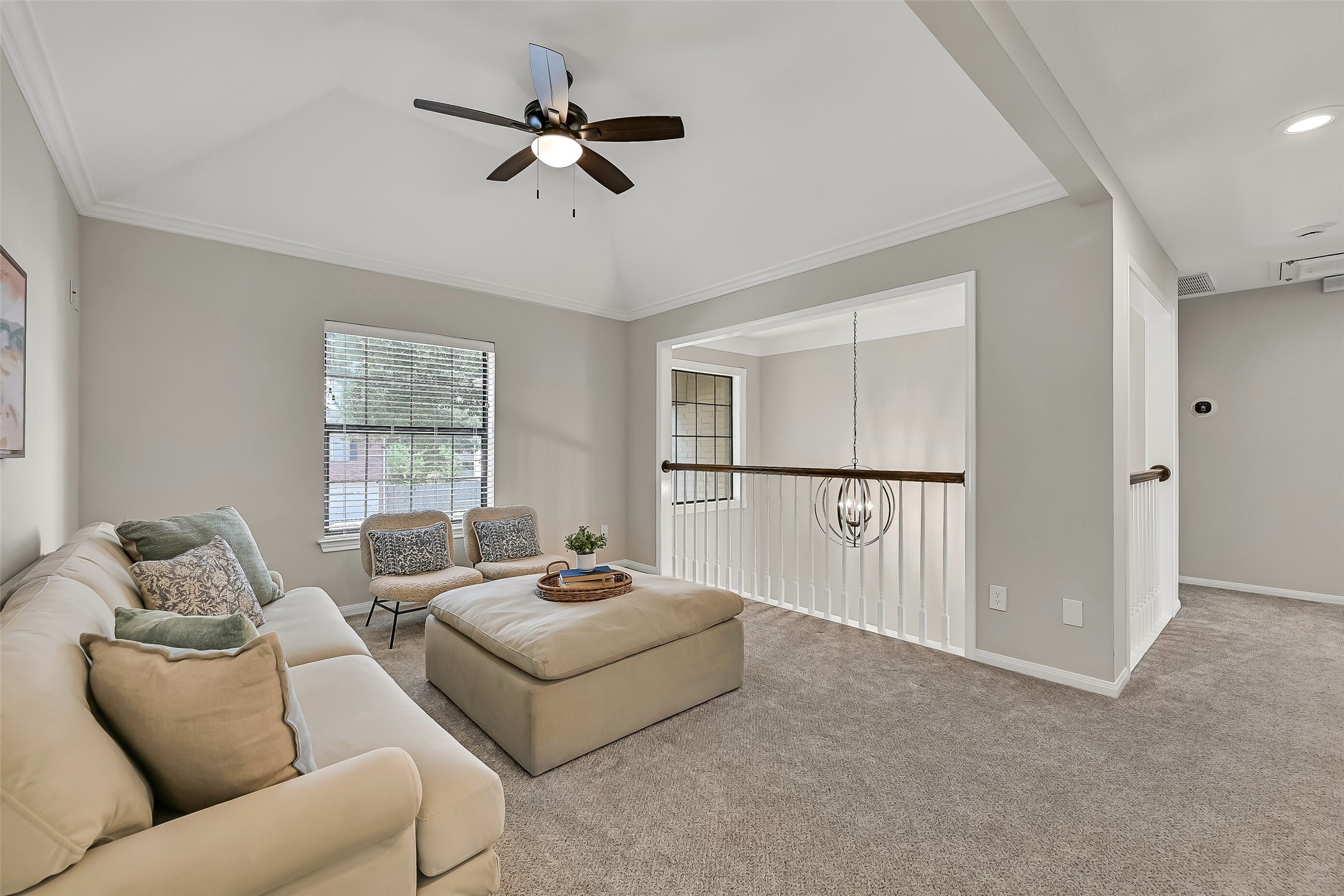 The upstairs gameroom serves as a central gathering space connecting the secondary bedrooms and baths. Neutral carpet, a tray ceiling and an open railing overlooking the foyer help the second floor feel bright, spacious and connected.