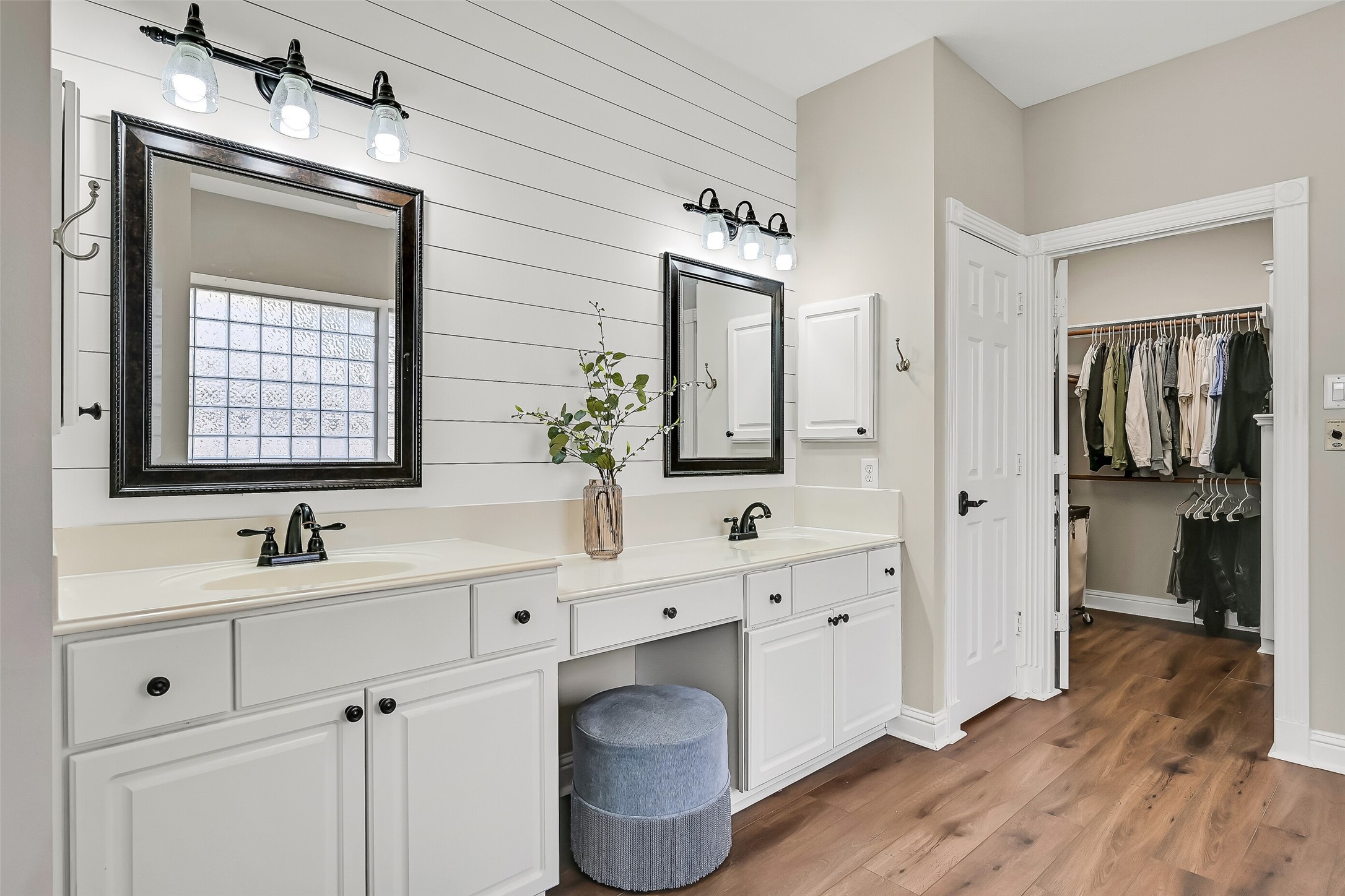 A closer view highlights the dual vanities with separate framed mirrors, generous counter space & dedicated makeup area. The oversized walk-in closet is located directly off the bath, providing extensive built-in storage just steps from the primary suite.