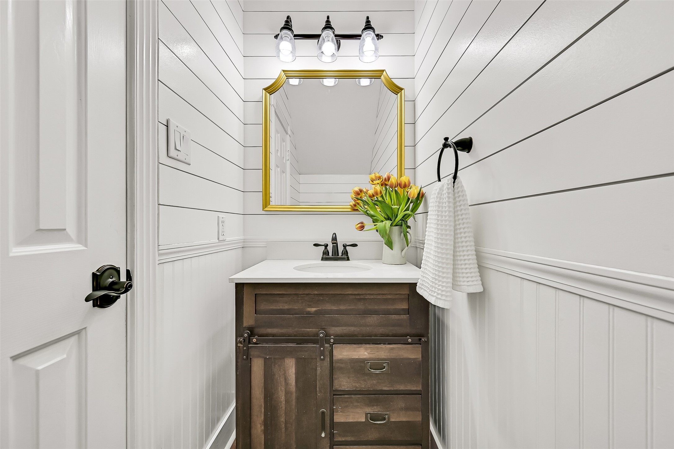 Conveniently located downstairs, the stylish powder bath features a pedestal sink, decorative mirror and charming wall detailing. Its convenient location serves guests without requiring access to any of the homes private bedroom spaces.