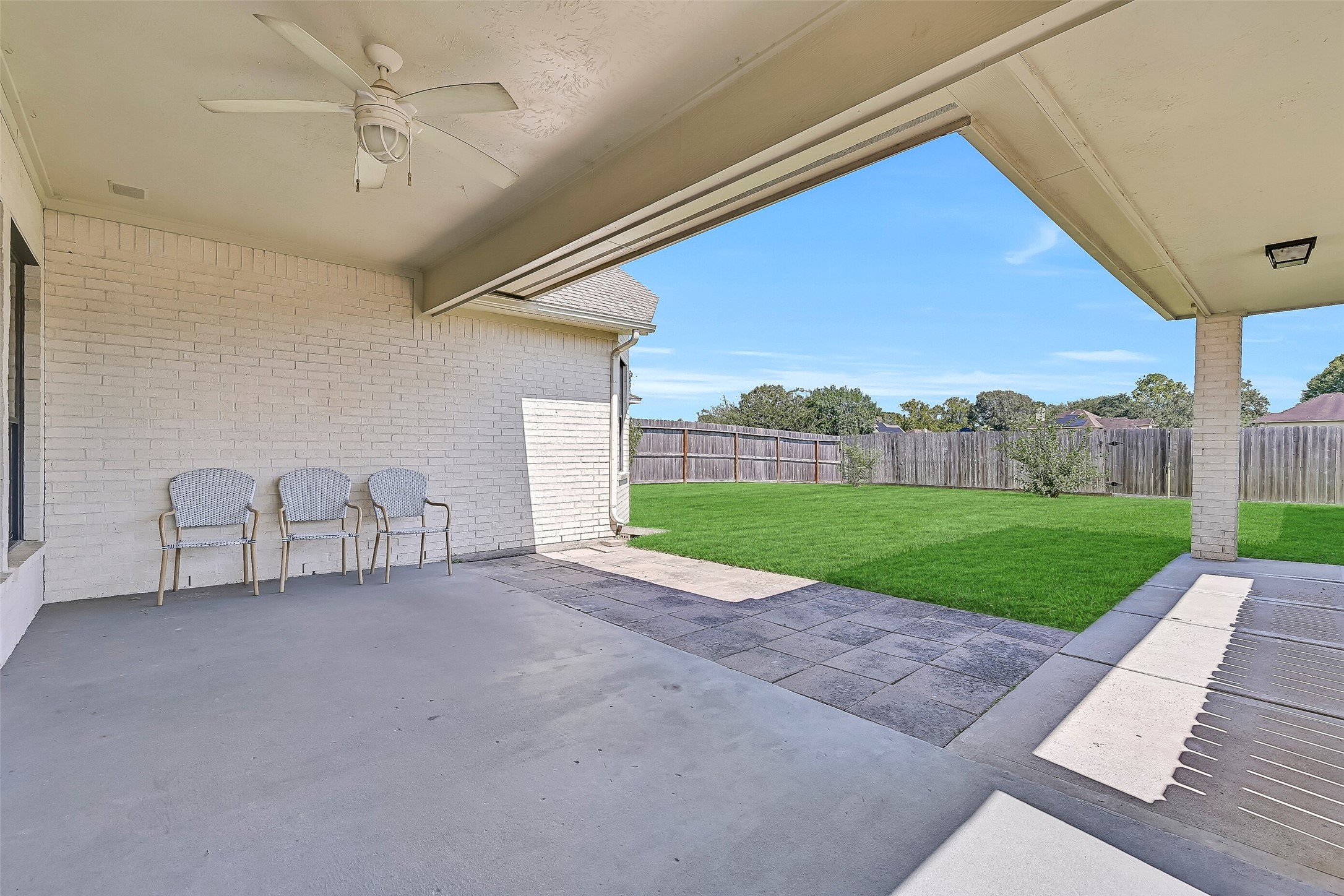 Step outside to a large covered patio extending across the rear of the home and connecting toward the detached garage. A ceiling fan and generous covered area create a shaded spot for outdoor dining, relaxing or entertaining throughout the year.