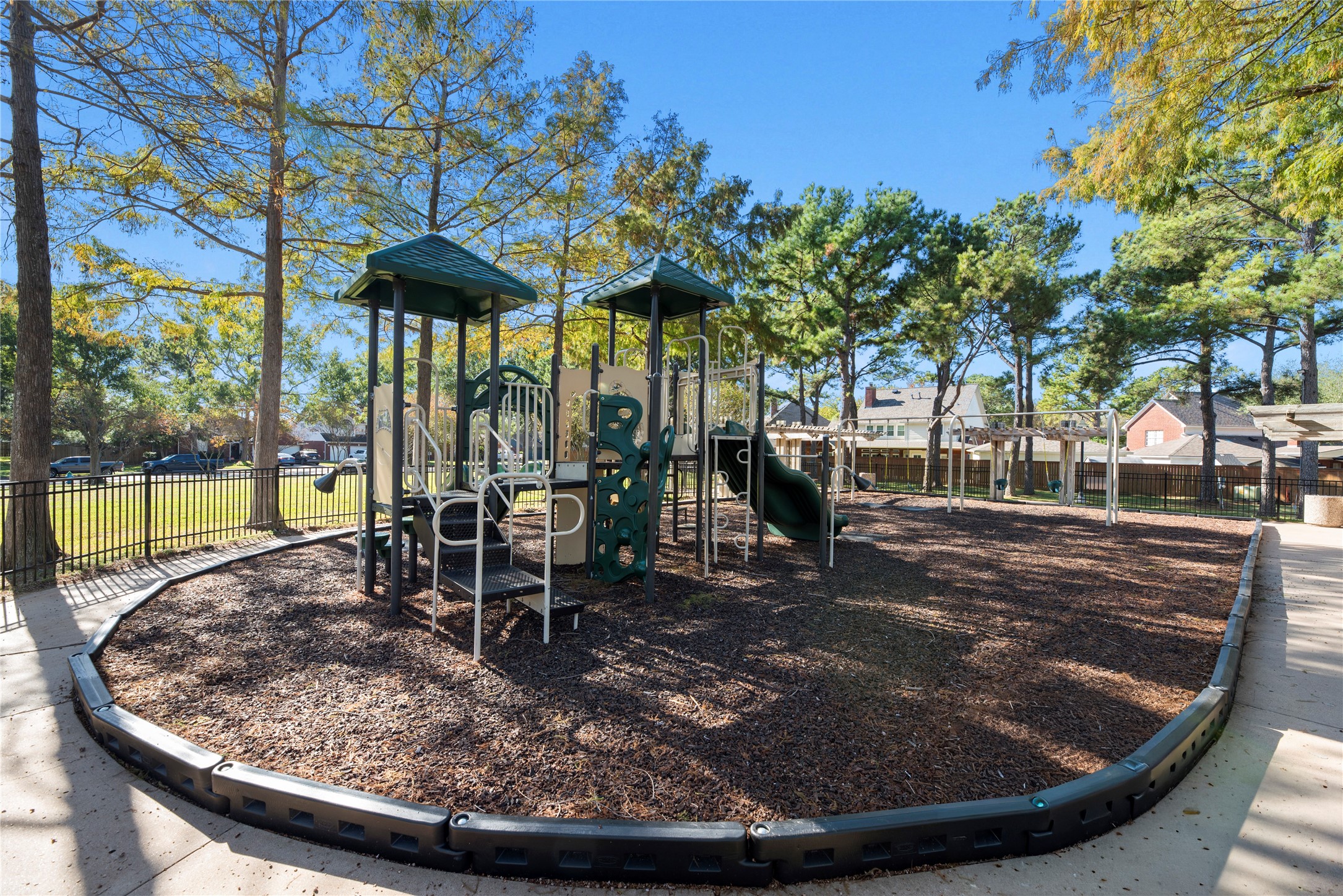 Another shaded neighborhood playground offers climbing, sliding & swinging fun in a welcoming outdoor setting beneath the trees.