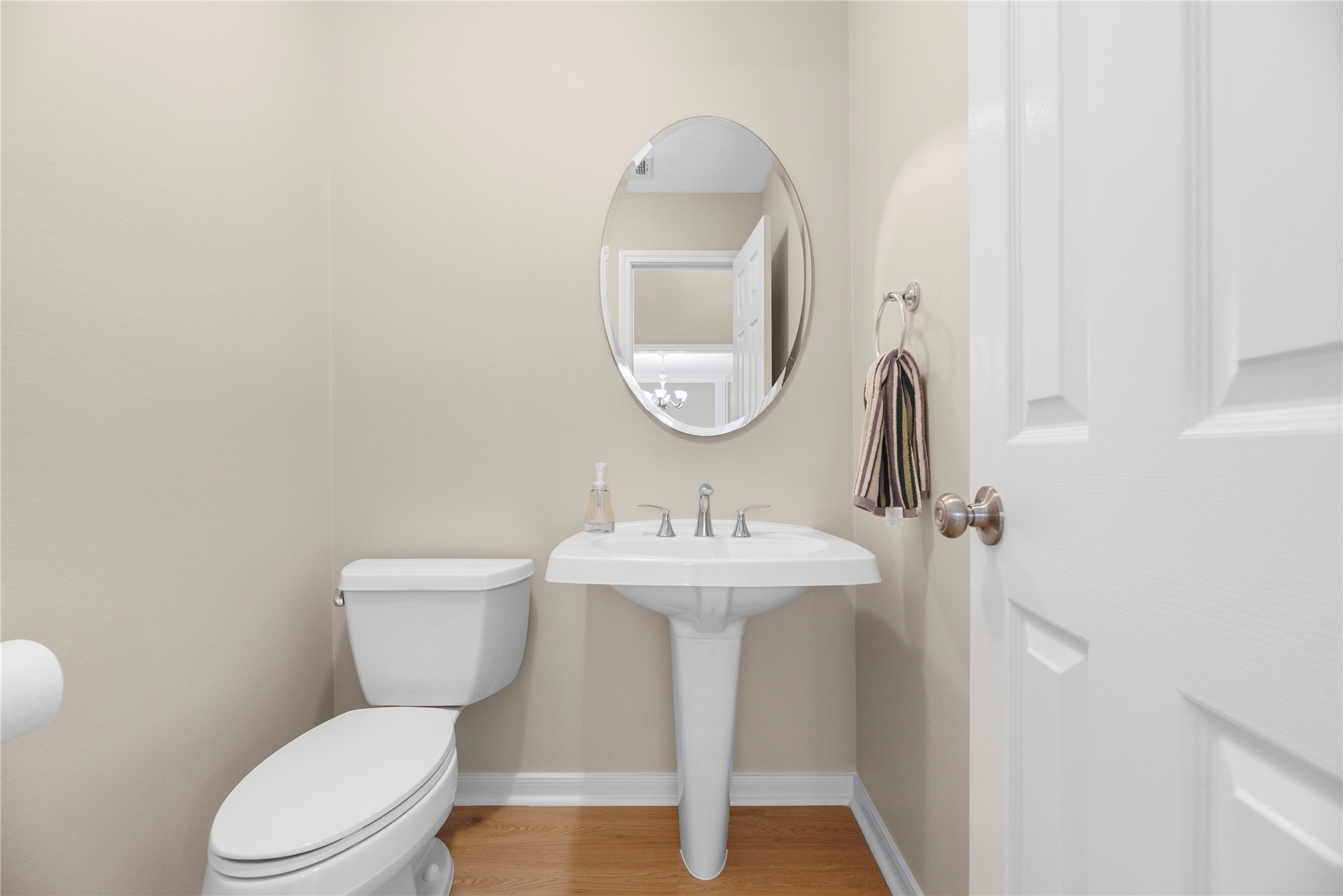 The 1st-floor powder bathroom is perfect for guests and everyday use, offering a classic pedestal sink and a beveled oval mirror for a polished finishing touch.