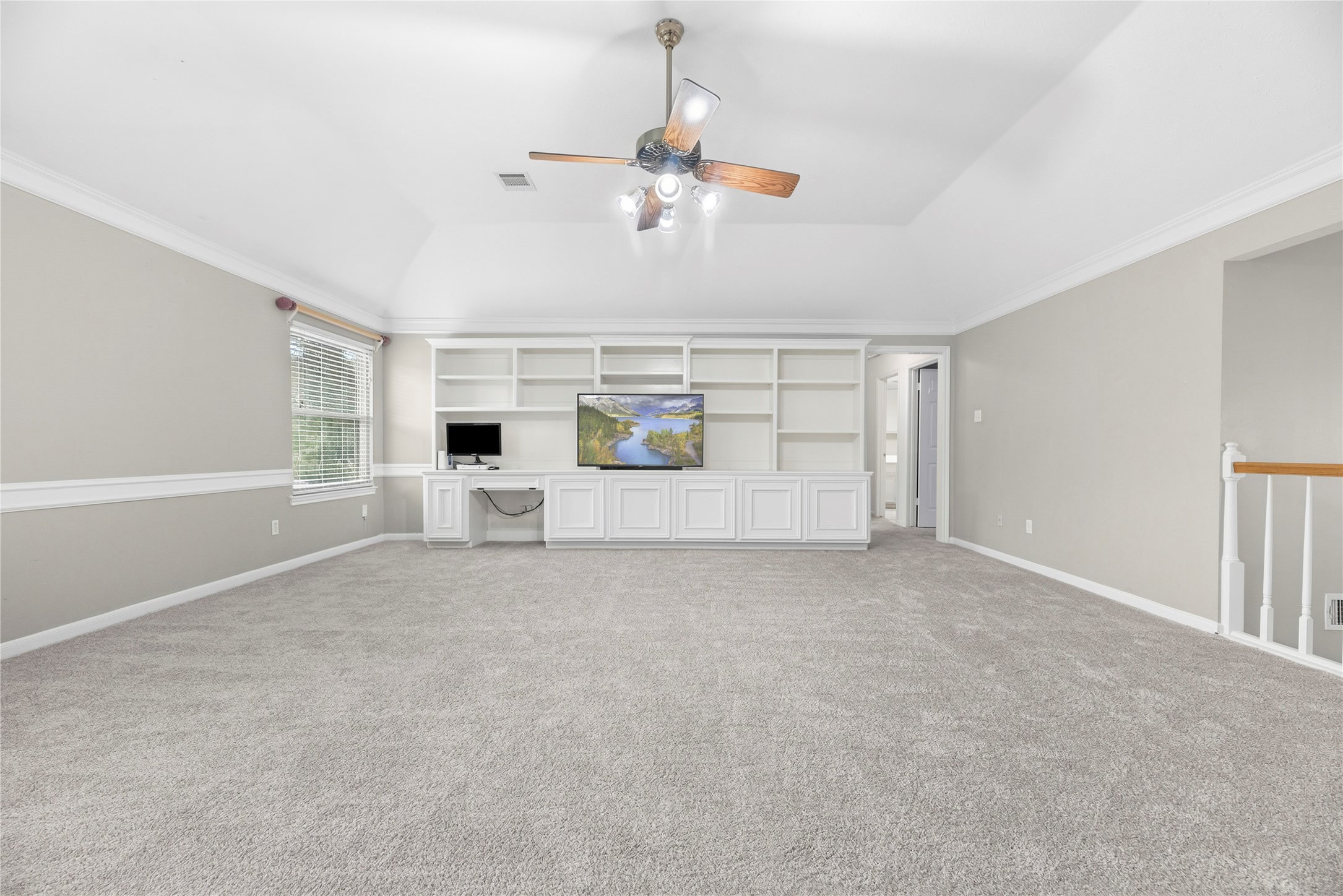 A full wall of custom built-ins offers open shelving, closed storage and a convenient desk, keeping games, electronics and everyday essentials organized without sacrificing style.