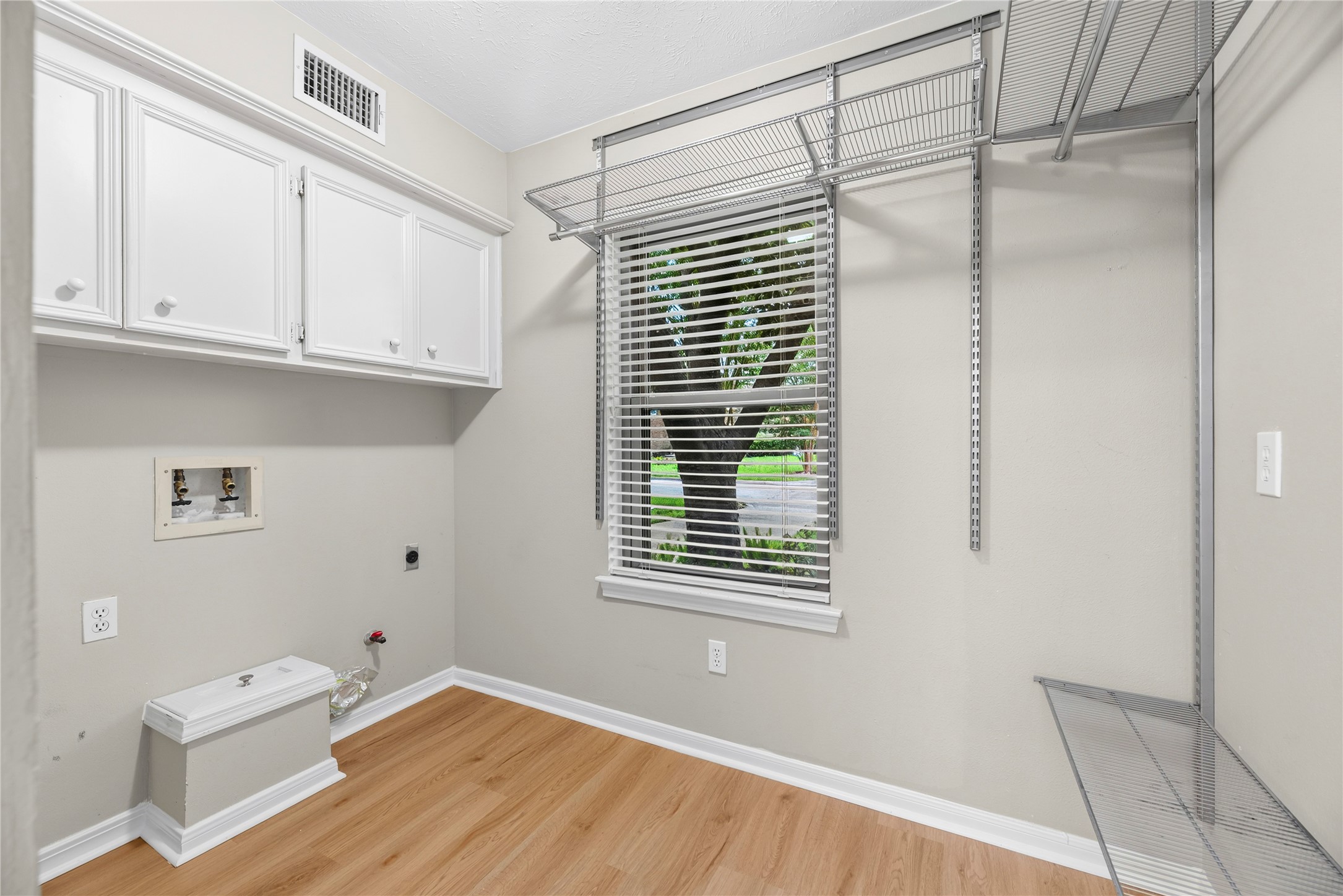 Conveniently located just off the kitchen, the utility room offers built-in cabinetry, extensive shelving & plenty of extra storage, along with an updated window & updated flooring.