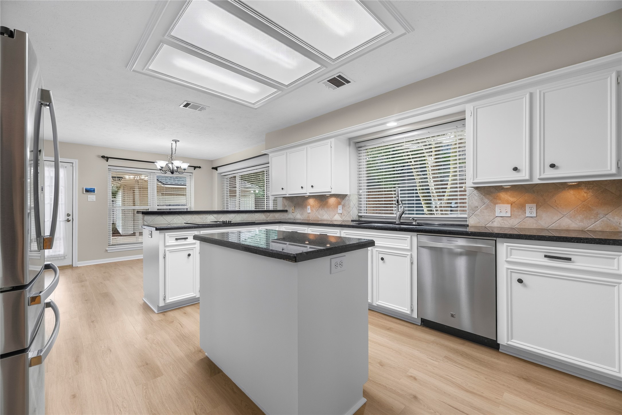 Show off your culinary skills in a kitchen designed to bring the joy into cooking. Find granite countertops, tumbled stone backsplash with under-cabinet lights, a center island plus extensive countertop space, built-in stainless-steel appliances, a sleek electric cooktop with an exhaust fan, bright overhead lighting plus a large window over the sink.