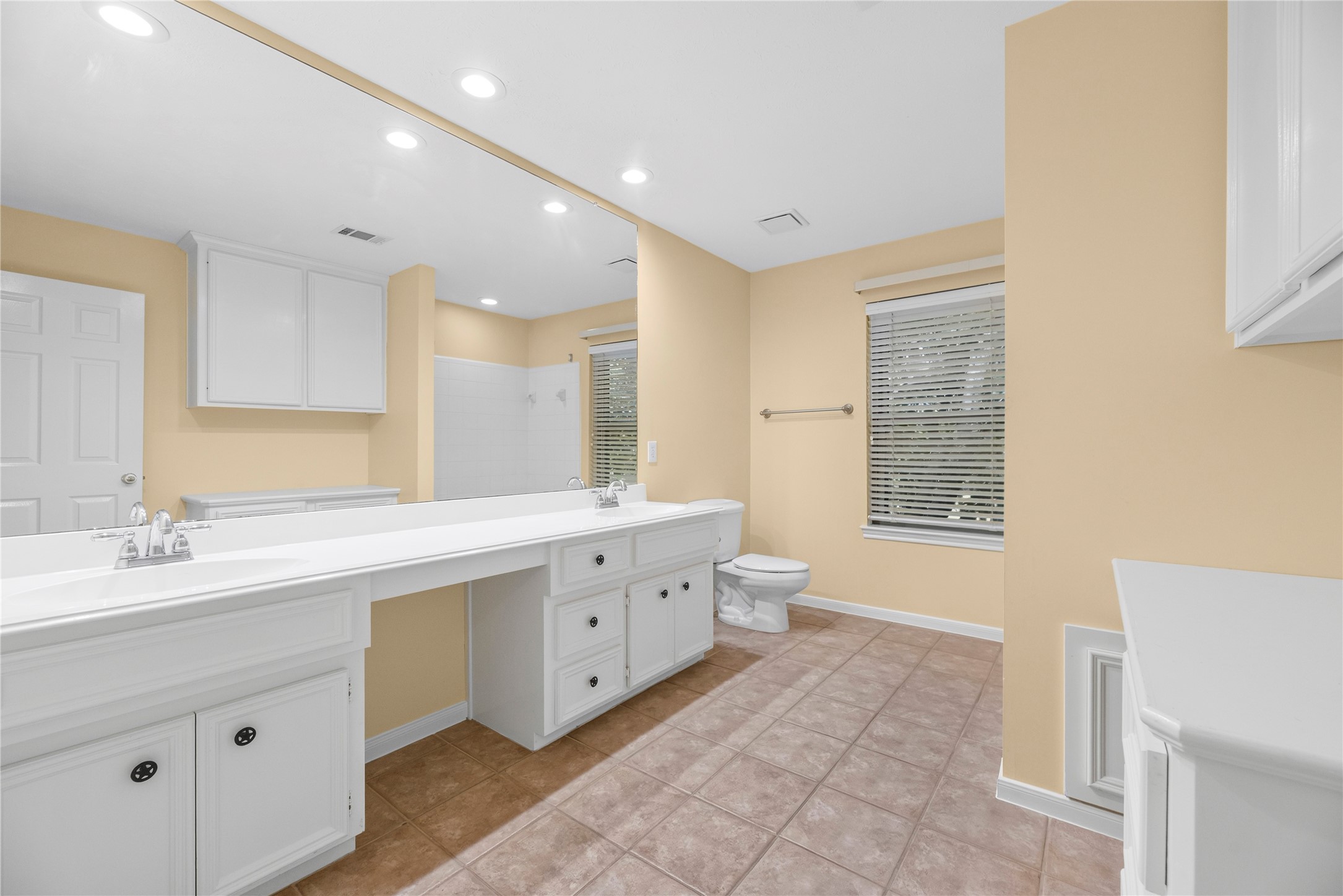 Sharing is easy in this roomy upstairs bathroom, where a dual-sink vanity with a full-width mirror and knee space for seated prep gives everyone room to get ready. A second vanity adds even more storage and prep space, while the tiled tub and shower enclosure completes the room for everyday convenience.
